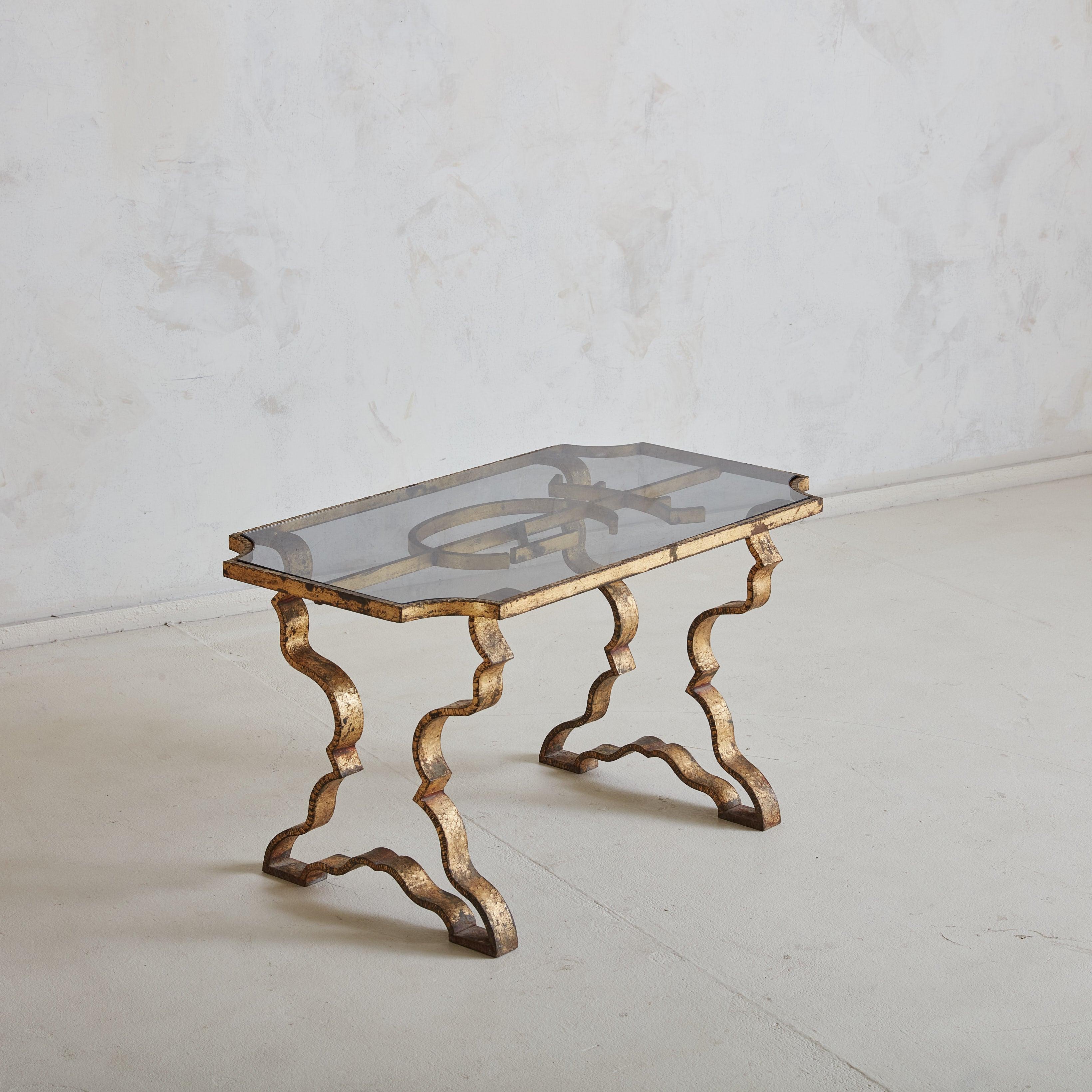D'un design français sculptural des années 1970, cette table basse associe un plateau en verre à une base en laiton martelé de manière complexe. Les pieds formés à la main, avec leurs courbes sinueuses et leurs surfaces texturées, captent la lumière