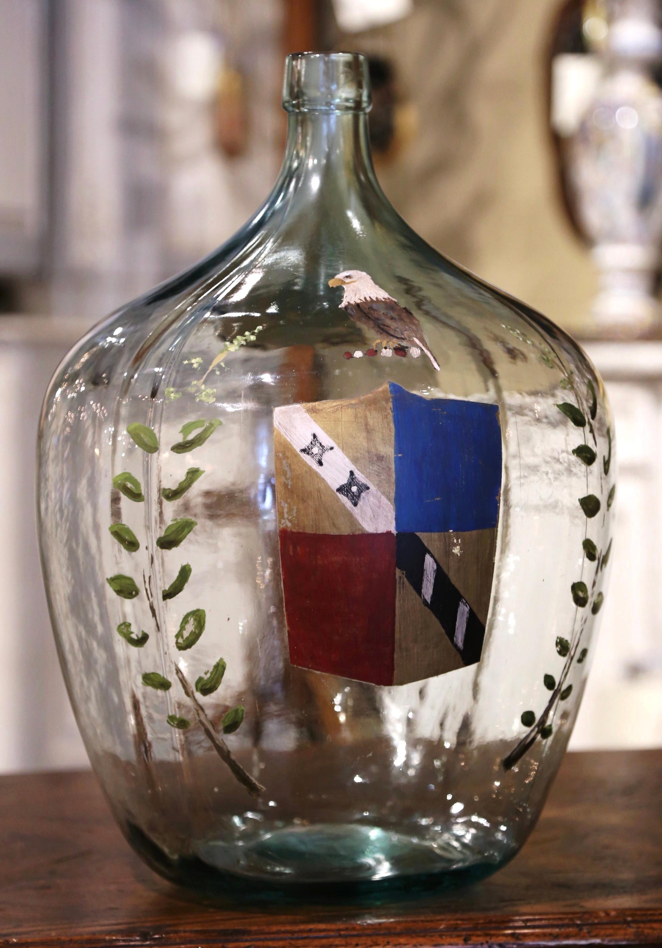 Bewahren Sie Ihre Weinkorken in dieser klassischen französischen Weinflasche auf! Diese hohe Glasflasche, die in Frankreich mundgeblasen wurde, zeigt ein mundgeblasenes Familienwappen mit einer Vogelfigur, das auf beiden Seiten mit Zweigen verziert