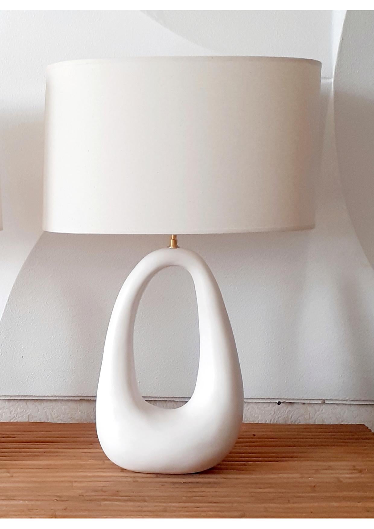- Elegant ceramic lamp with shade, handmade in Parisian workshop by Elsa Foulon Studio.
Mineral, organic and sensual shape.
Cotton shade, brass structure, soft white enameled ceramic, screw bulb.
UL listed electricity on request.
Measures: