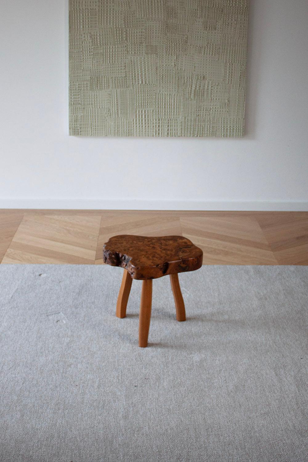 available is a hand-carved three-legged chair made from burl wood.
the stool stands on three legs which have a very elegant curve. the stool top has a stunning wood grain. 
The stool is one of a set of four and can also be purchased as a complete