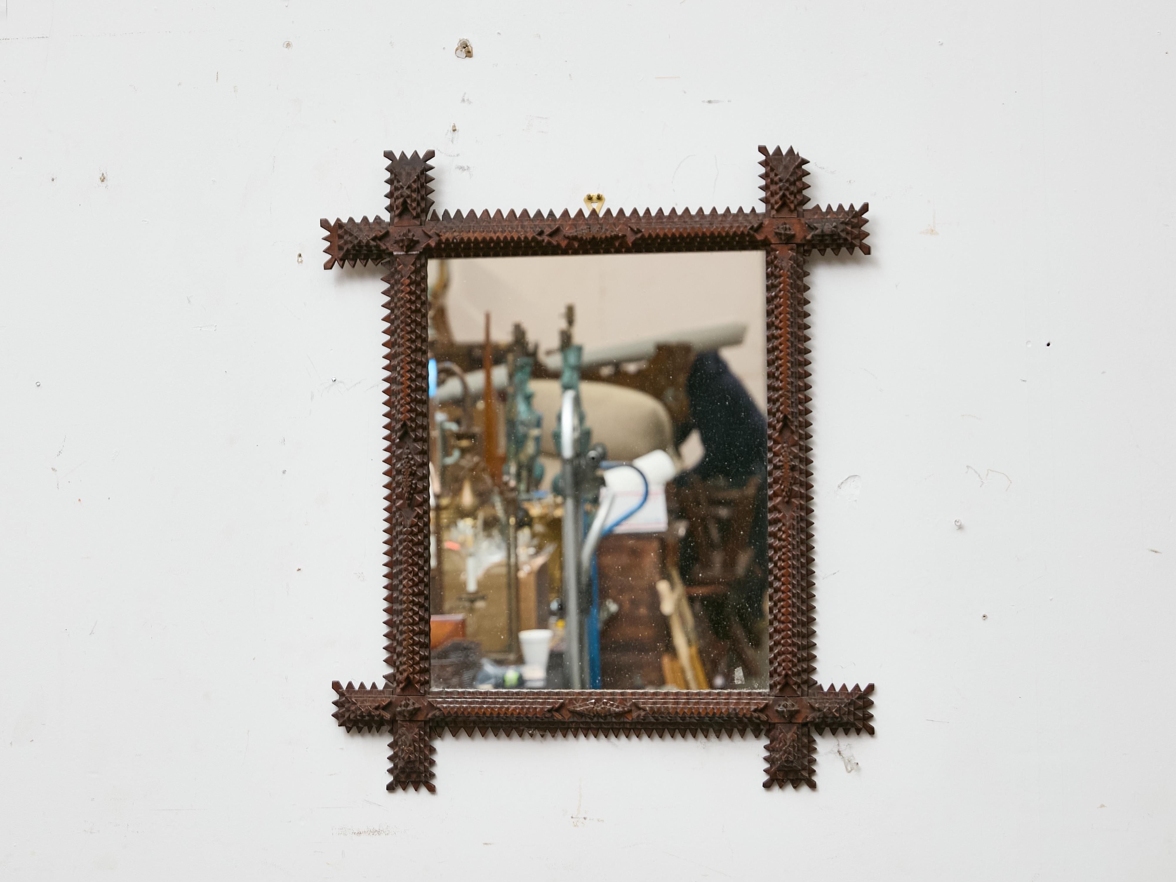 A compact yet visually impactful example of French Tramp Art, this mirror dates to around 1900 and features a deeply carved frame with the signature layered notching technique. The frame steps outward at the corners in dramatic “cross” projections,