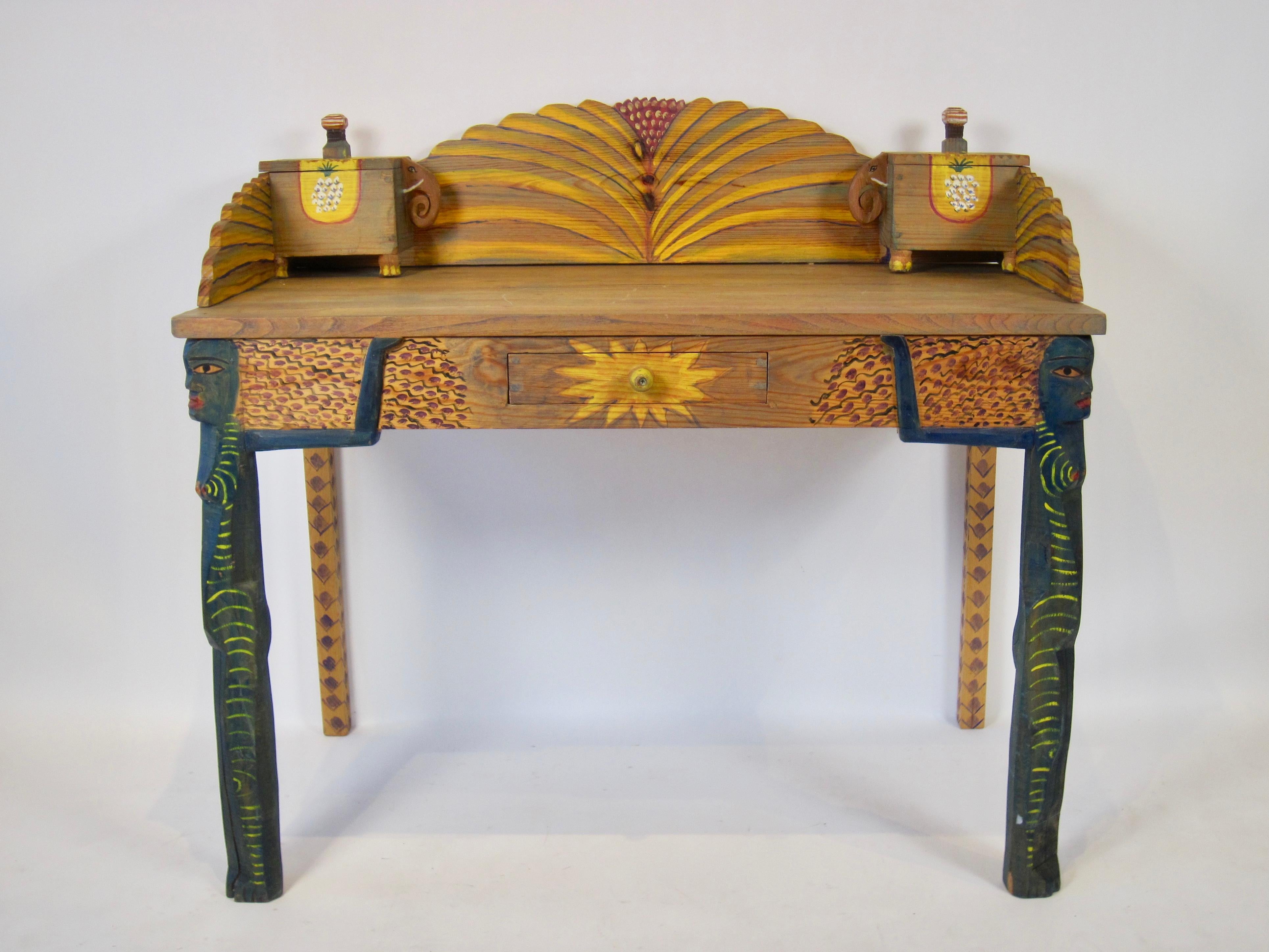Gérard Rigot's (b.1929) colorful hand painted oak Folk Art desk. From the aboriginal women painted on the two front legs to the pineapples painted on the elephant storage boxes to the colorful patterns painted throughout this hand crafted piece, it