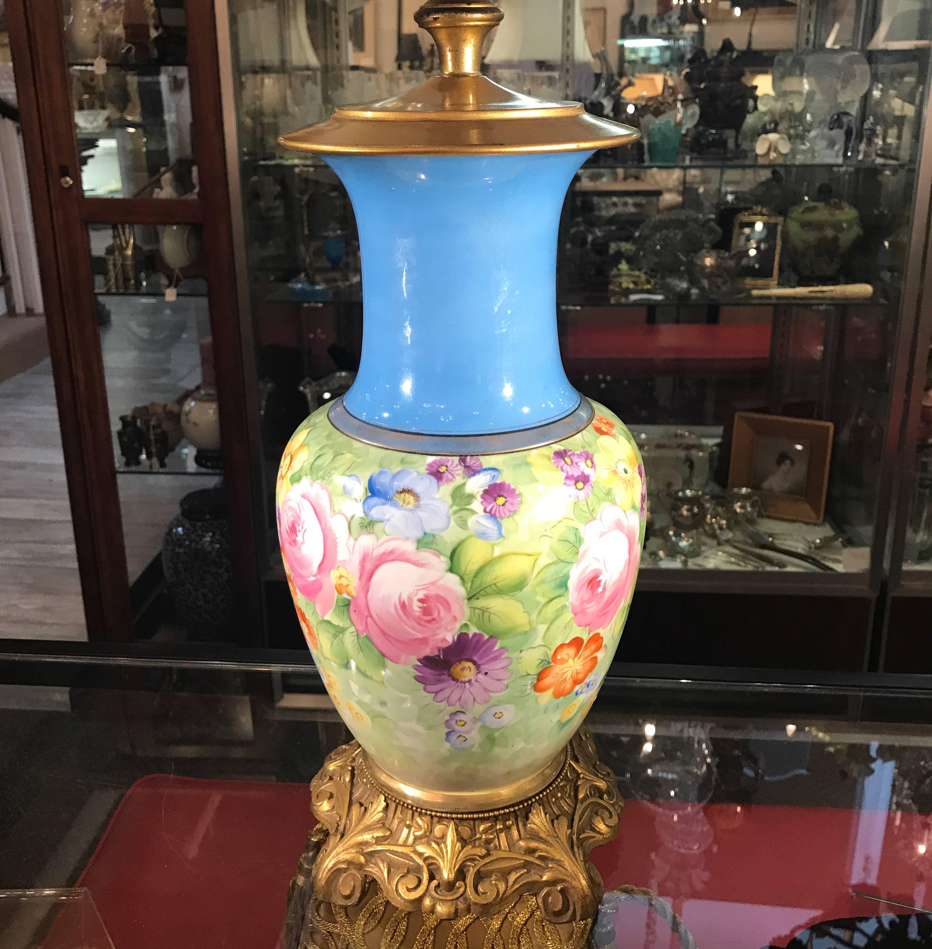Vibrant hand-painted French porcelain floral vase lamp. The late 19th century vase electrified in the 1920s with a git metal base. The Celeste blue neck with floral body and gilt highlights. The shade is for Photographic purposes only and not