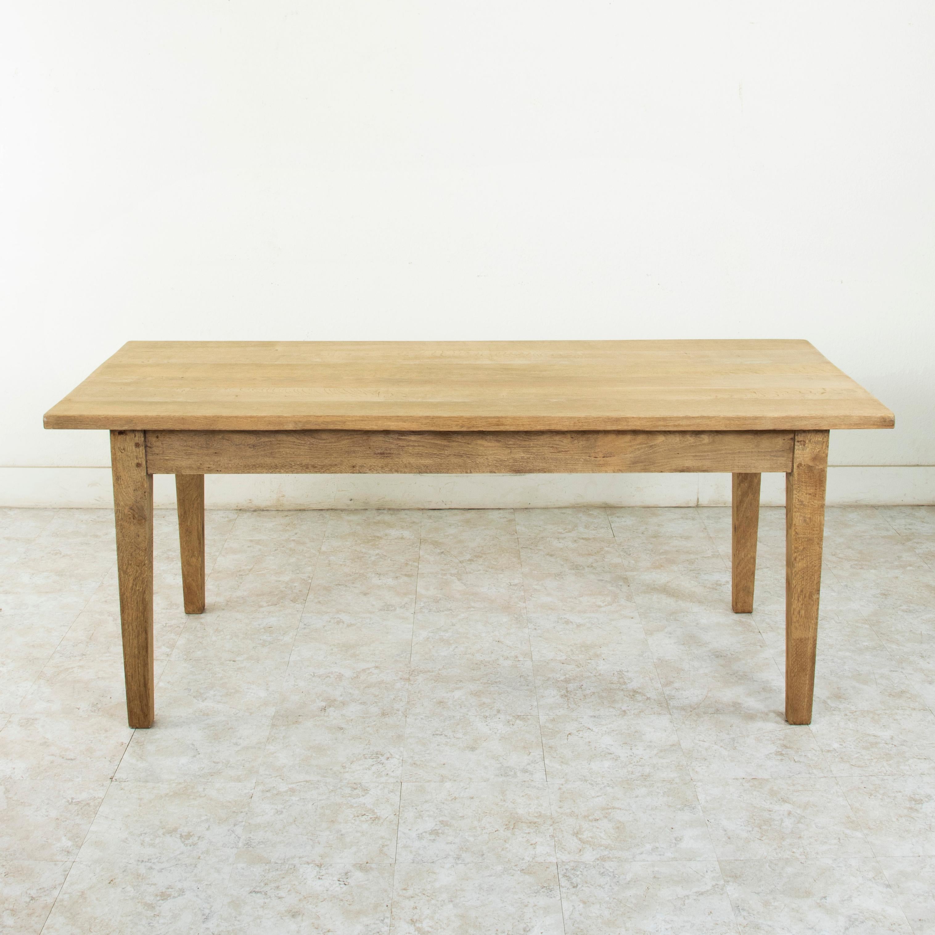 This turn of the 20th century oak farm table or dining table from the Le Perche, a sub-region of Normandy, France, features a top constructed of six planks of wood. Joined by splines that run the entire length of the table. This construction