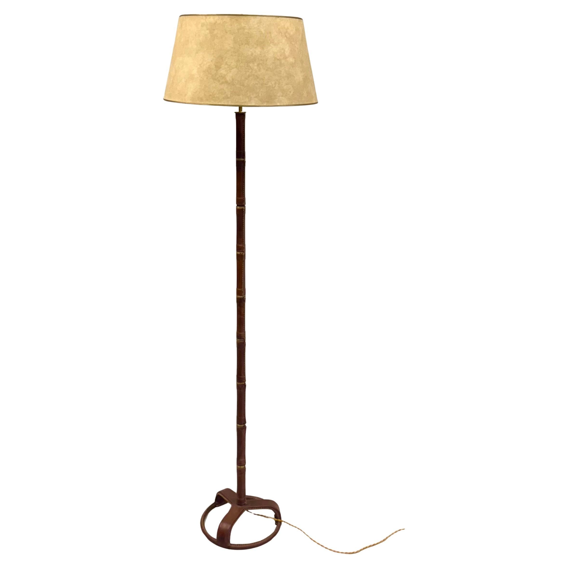 An Elegant and Timeless French Mid-Century Modern Hand Stitched, Faux Bamboo, Brown Leather Floor Lamp by Jacques Adnet, France, circa 1955. This classic hand made model from the renowned French designer, Jacques Adnet is sought after as an icon of