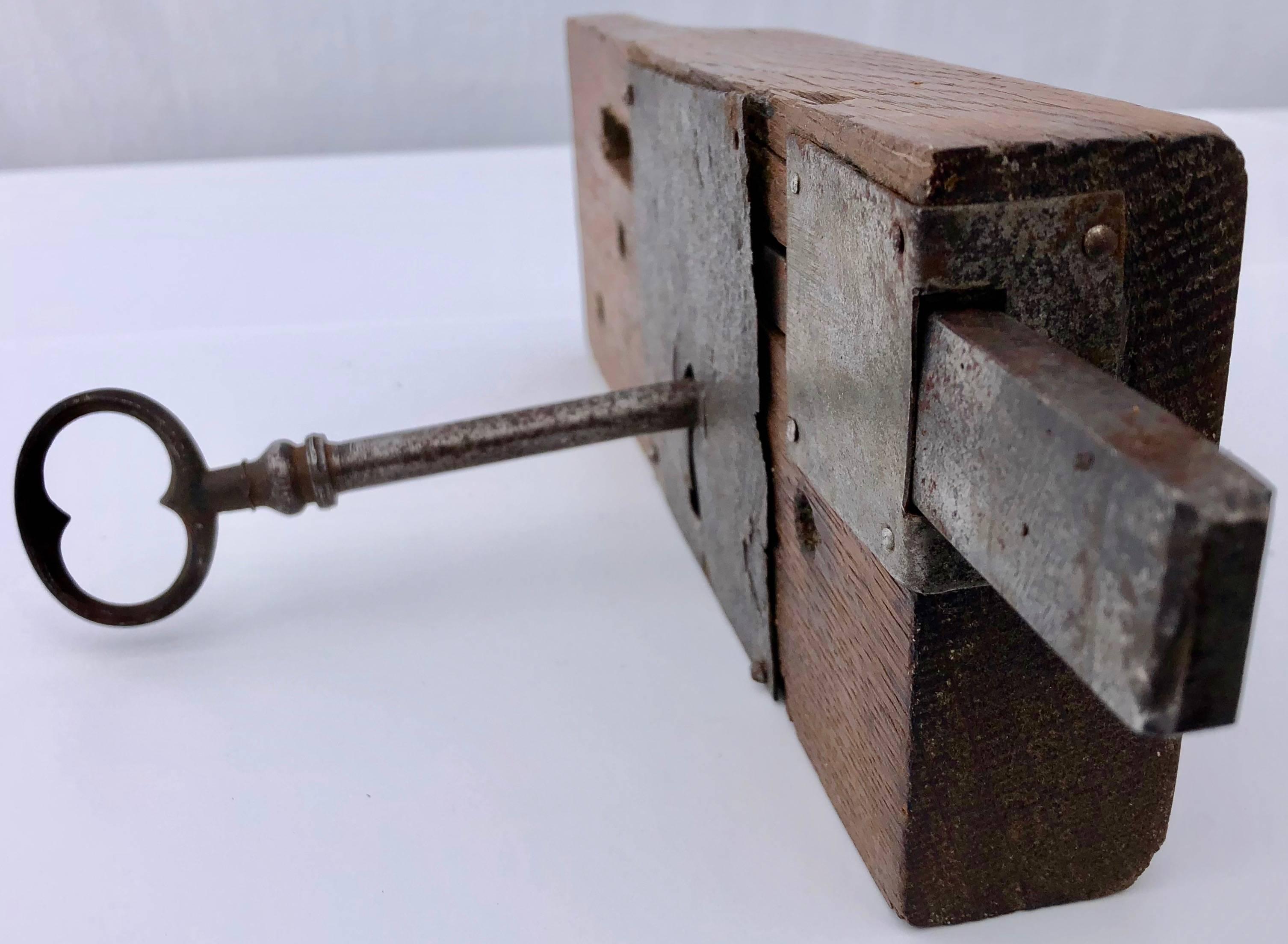This 18th-19th century French hand-wrought iron mortise mount lock has a deadbolt that operates from both sides with its own included key. It is mounted on its original wood. A unique, functioning French period lock that would add immediate charm to