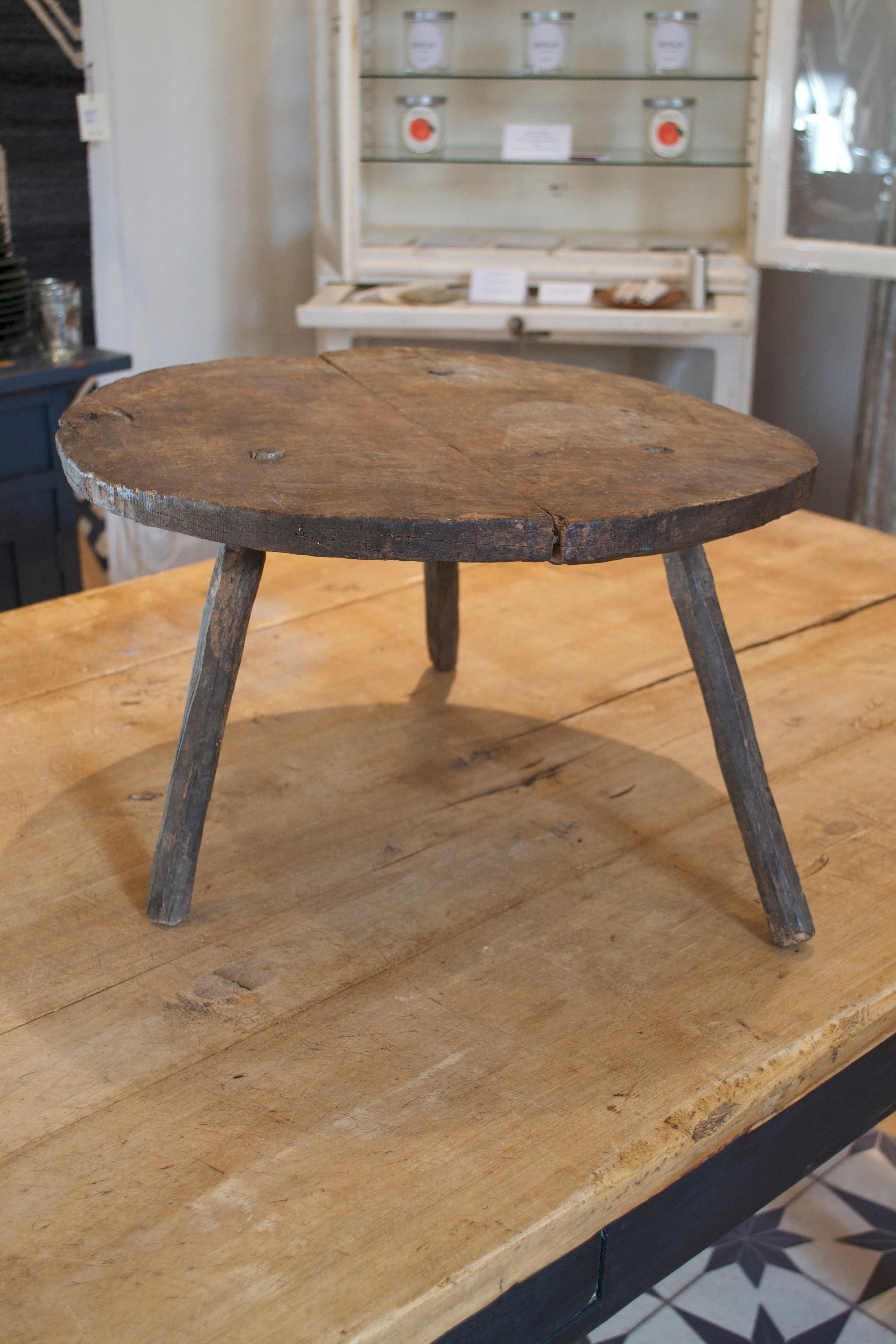 A rustic handmade French side table. Low to the ground with characteristics of handmade craft and age.