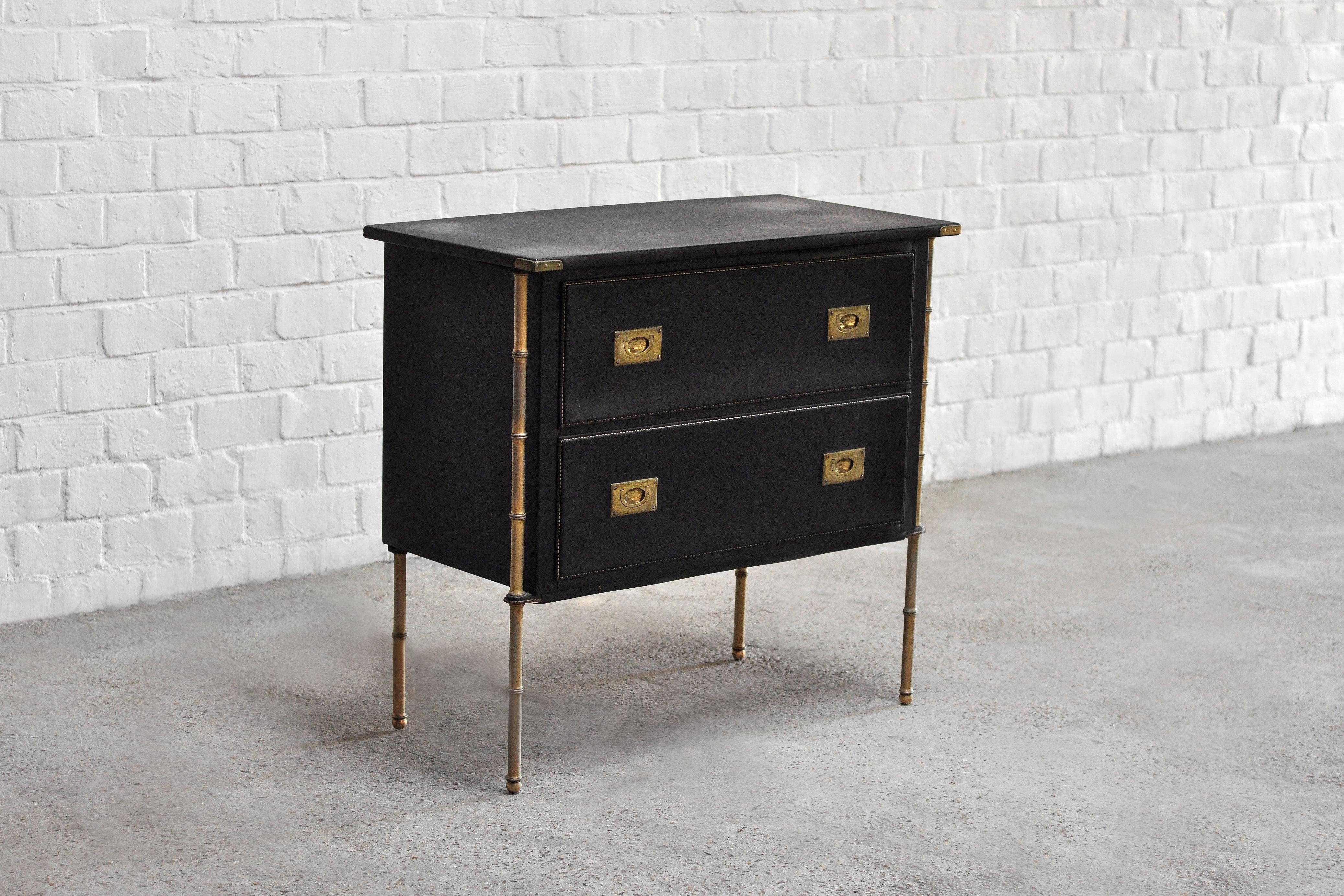 An important French Mid-Century hand-stitched leather commode by Jacques Adnet. The design of this piece is subtly balanced with muted black leather and burnished brass coloration. the faux bamboo brass legs are an iconic style detail for french