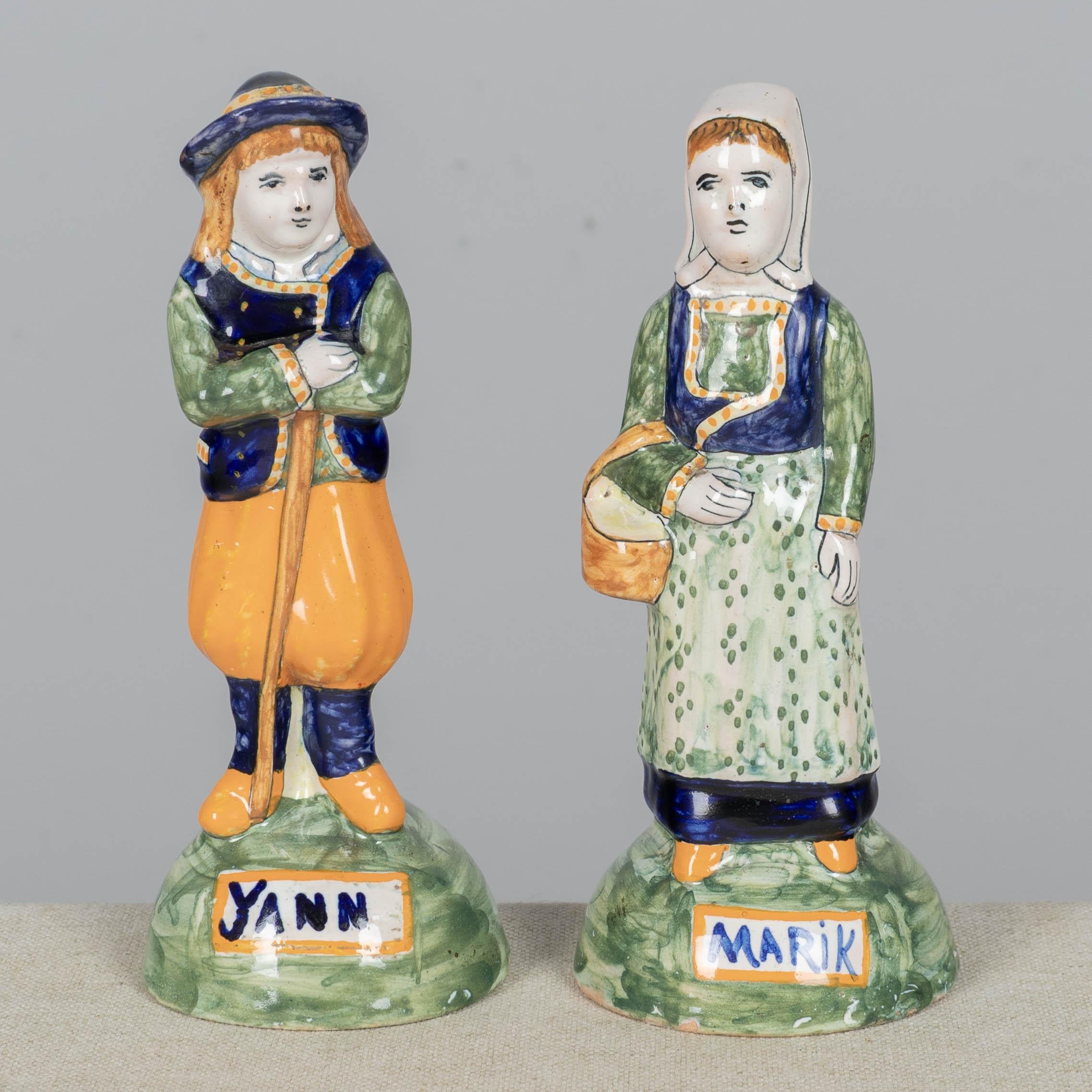 Pareja de estatuas o figurillas francesas de loza de Henriot Quimper, de Yann y Marik. Loza esmaltada policromada, pintada a mano en naranja, verde y azul. Estas figuritas bretonas forman parte de la tradición de representar encantadoras y rústicas