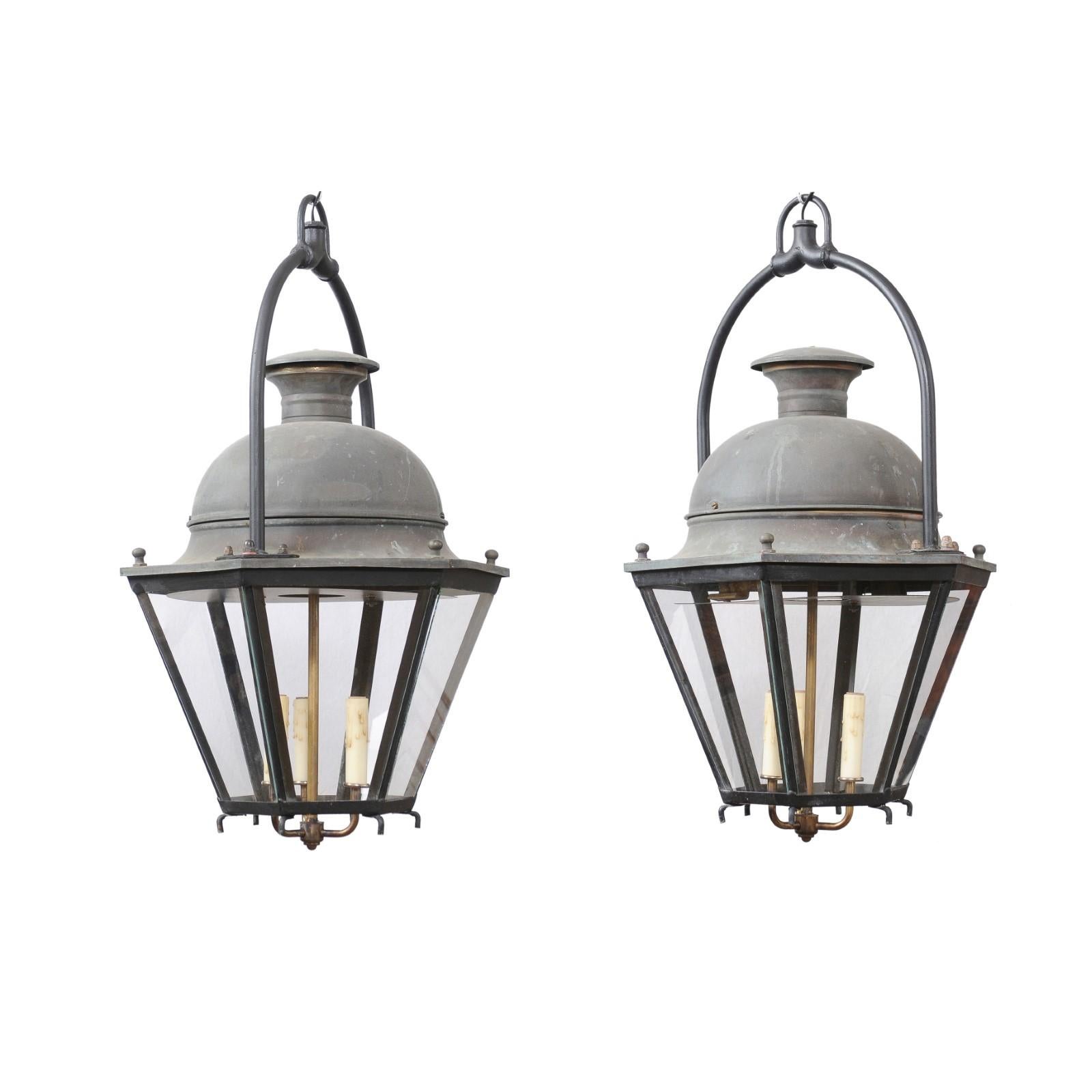 Two French hexagonal copper lanterns from the 20th century with glass panels, domed top and three lights. These two French hexagonal copper lanterns, each sold individually, are captivating pieces that seamlessly blend timeless elegance with modern