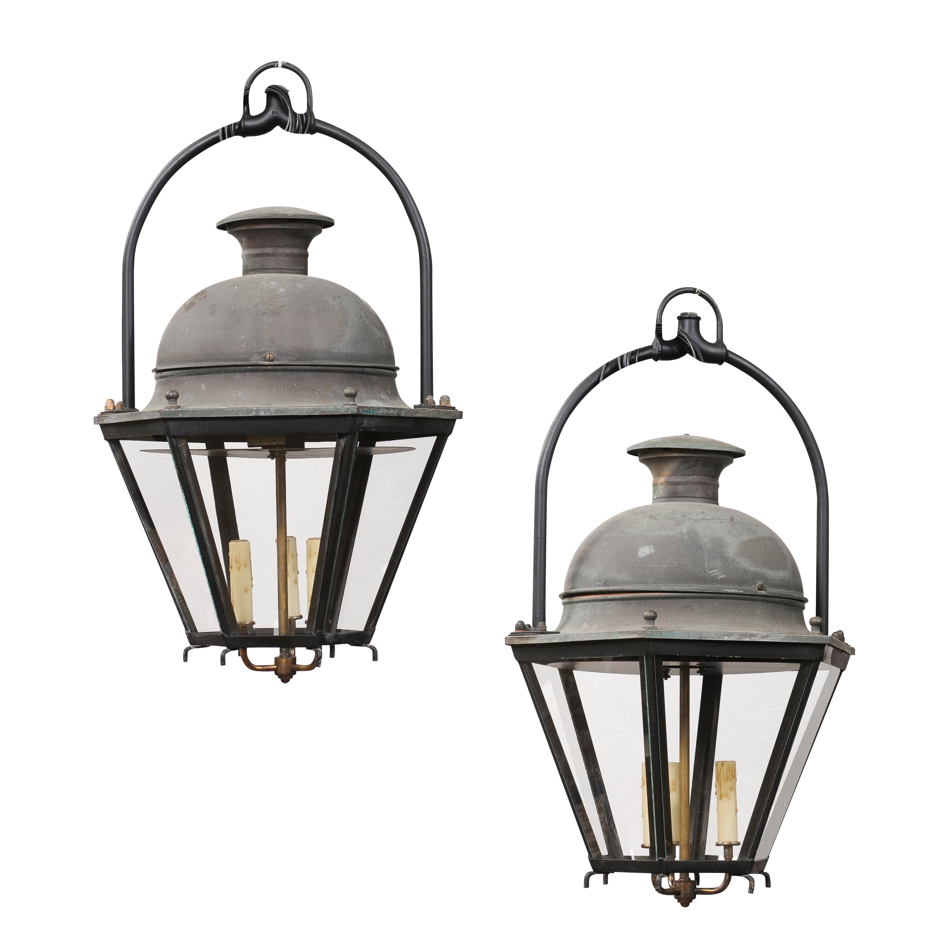French three-light copper lanterns with hexagonal bodies, glass panels and domes, sold each. Radiating warmth and vintage elegance, these French copper lanterns from the 20th century seamlessly intertwine traditional artistry with timeless charm.