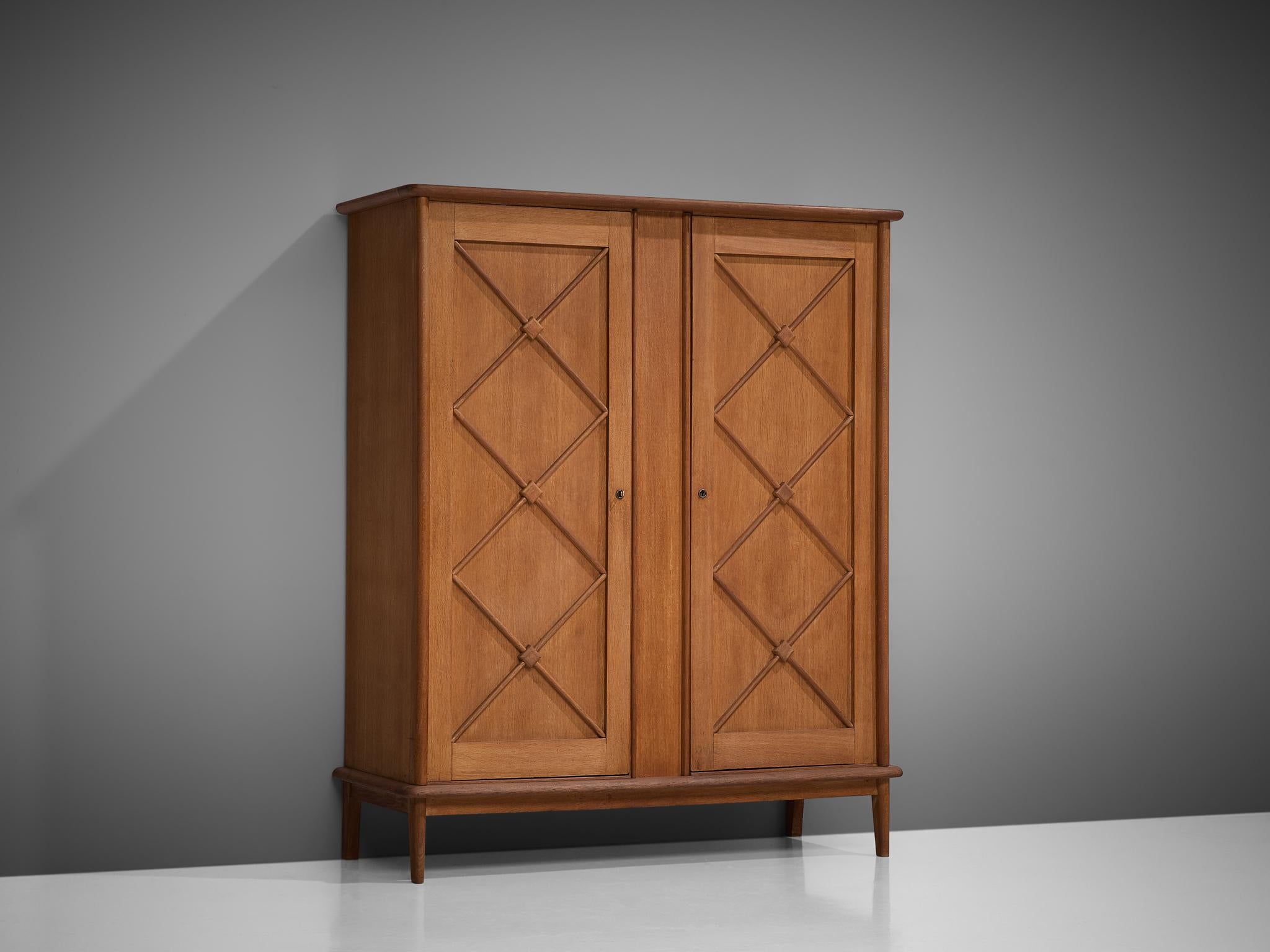 Cabinet, oak, France, 1960s

An elegant case piece in oak that features geometric details in the doors. The high board is lifted from the ground by slim, conical legs that give the solid looking body a more airy appearance. The cabinet offers