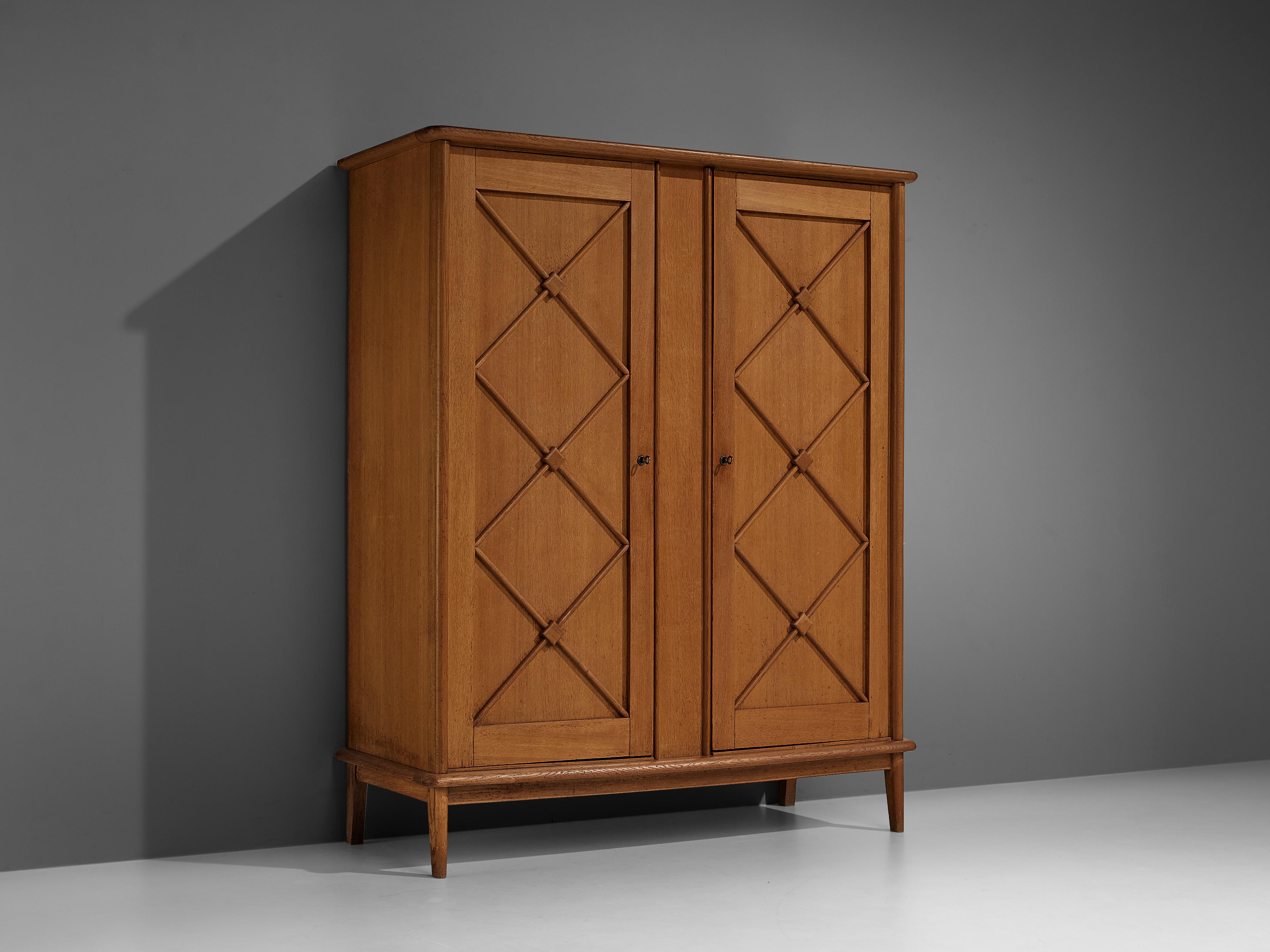 wardrobe, oak, France, 1960s

An elegant armoire in oak that embodies geometrical shapes that specialize the design and highlight the admirable craftsmanship. The corpus is lifted from the ground by slim, conical legs that give the solid looking