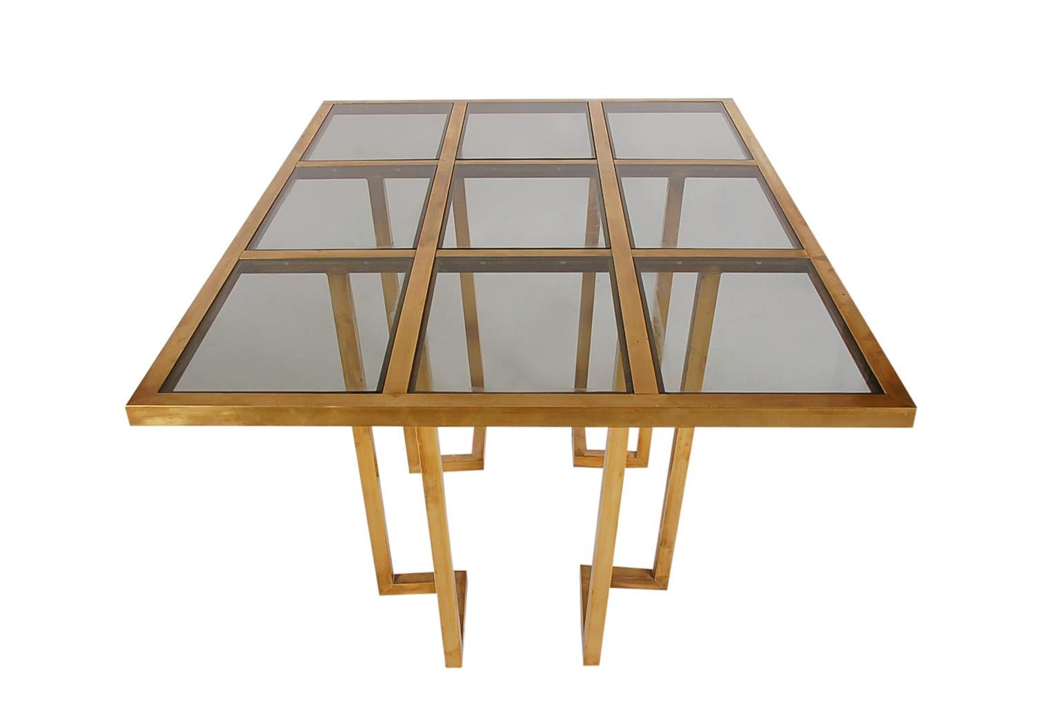 A gorgeous midcentury brass dining table from France, circa 1960s. It features a grid design with patinated brass and inlayed glass. Nice warm overall patina. Ready for use.