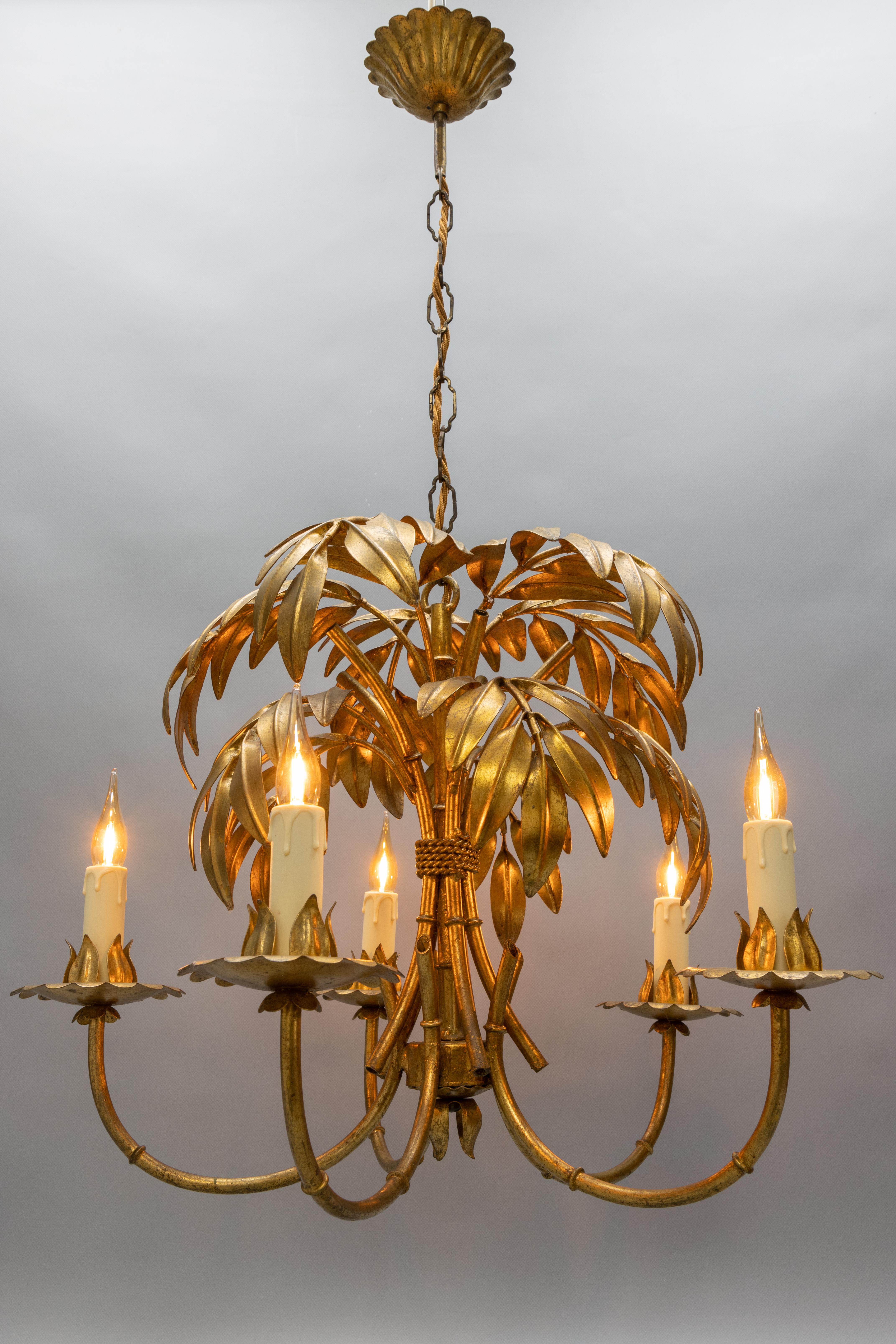 Hollywood Regency gilt metal bamboo palm five-light chandelier, France, ca. the 1950s.
This exceptional and beautiful chandelier is made of gilt metal and is adorned with beautifully shaped large bamboo palm leaves. Each of the five light chandelier
