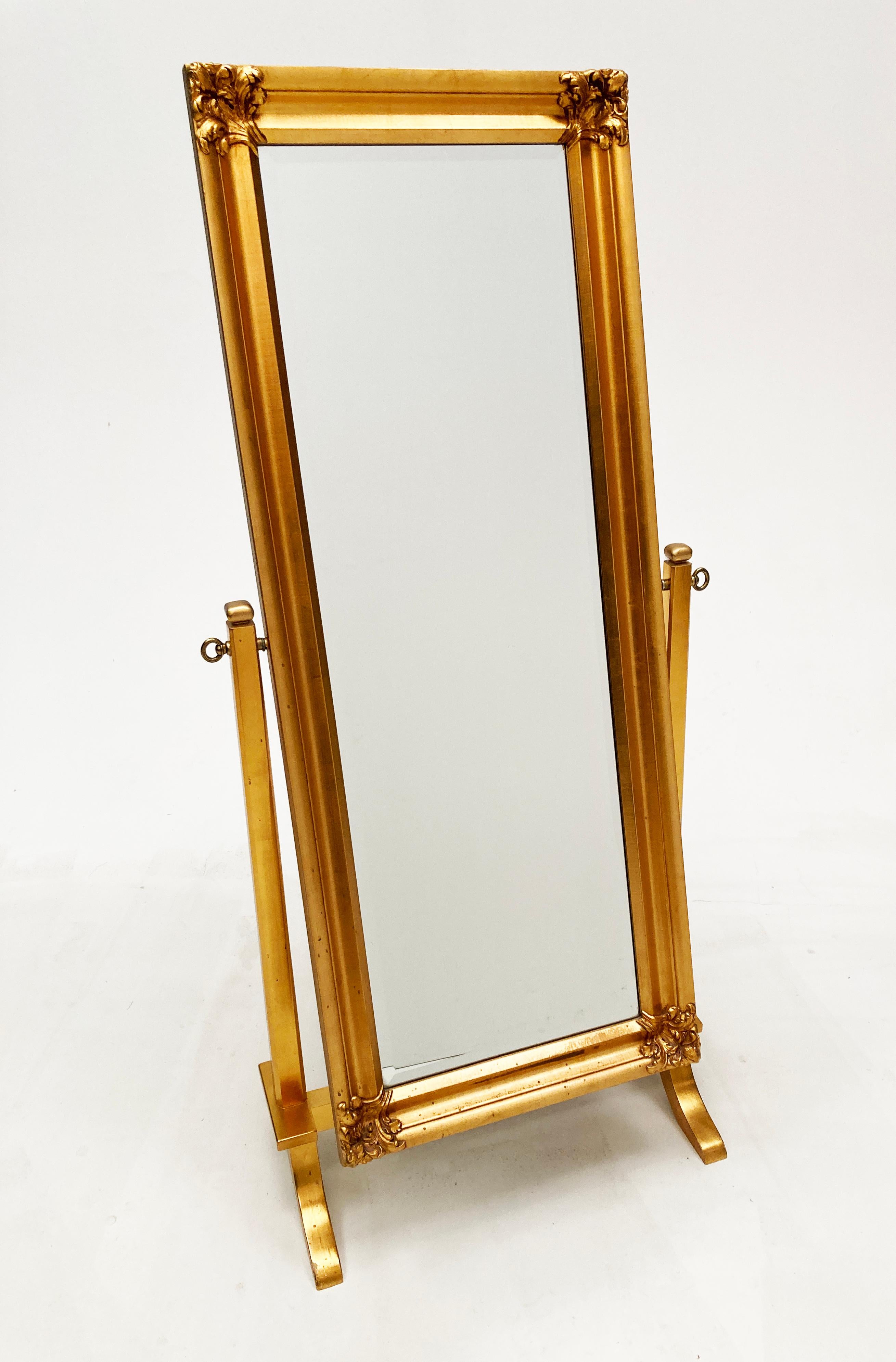 Fabulous gilt wood cheval mirror infuses a French vibe with a touch of Hollywood Regency. Custom crafted, this beveled glass mirror sits on a four-leg cradle base. The framework of the mirror is simple, yet showcases ornate flora corner molding that