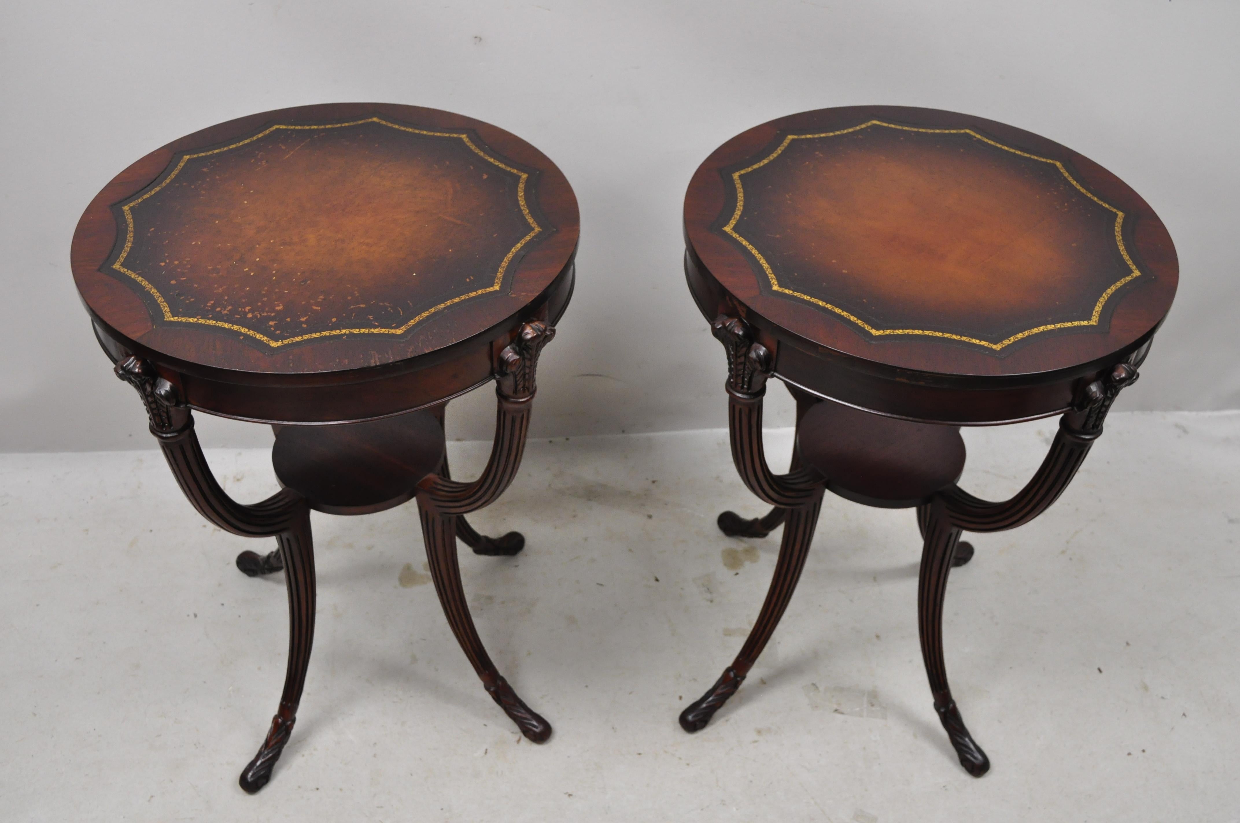 French Hollywood Regency Grosfeld House style Plume carved leather top mahogany end tables - a pair. Item features tooled leather tops, plume carved accents, lower shelf, saber legs, solid wood construction, nicely carved details, very nice antique