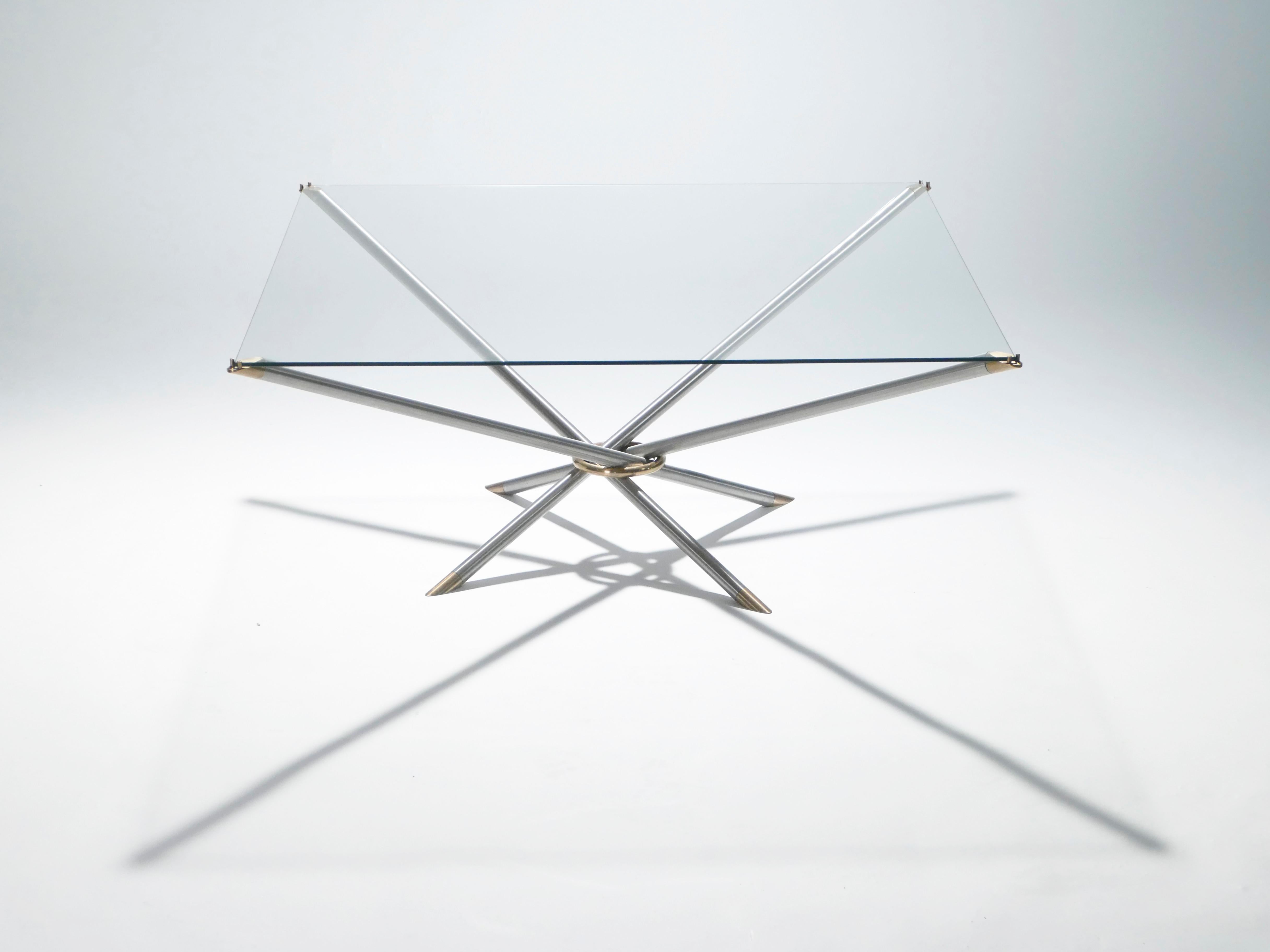 This metal, brass, and glass coffee table has the sleek, yet decadent, look that’s reminiscent of French designer Georges Geffroy. The smooth metal legs are crossed and kept together with a brass loop, creating an inventive, geometric design that