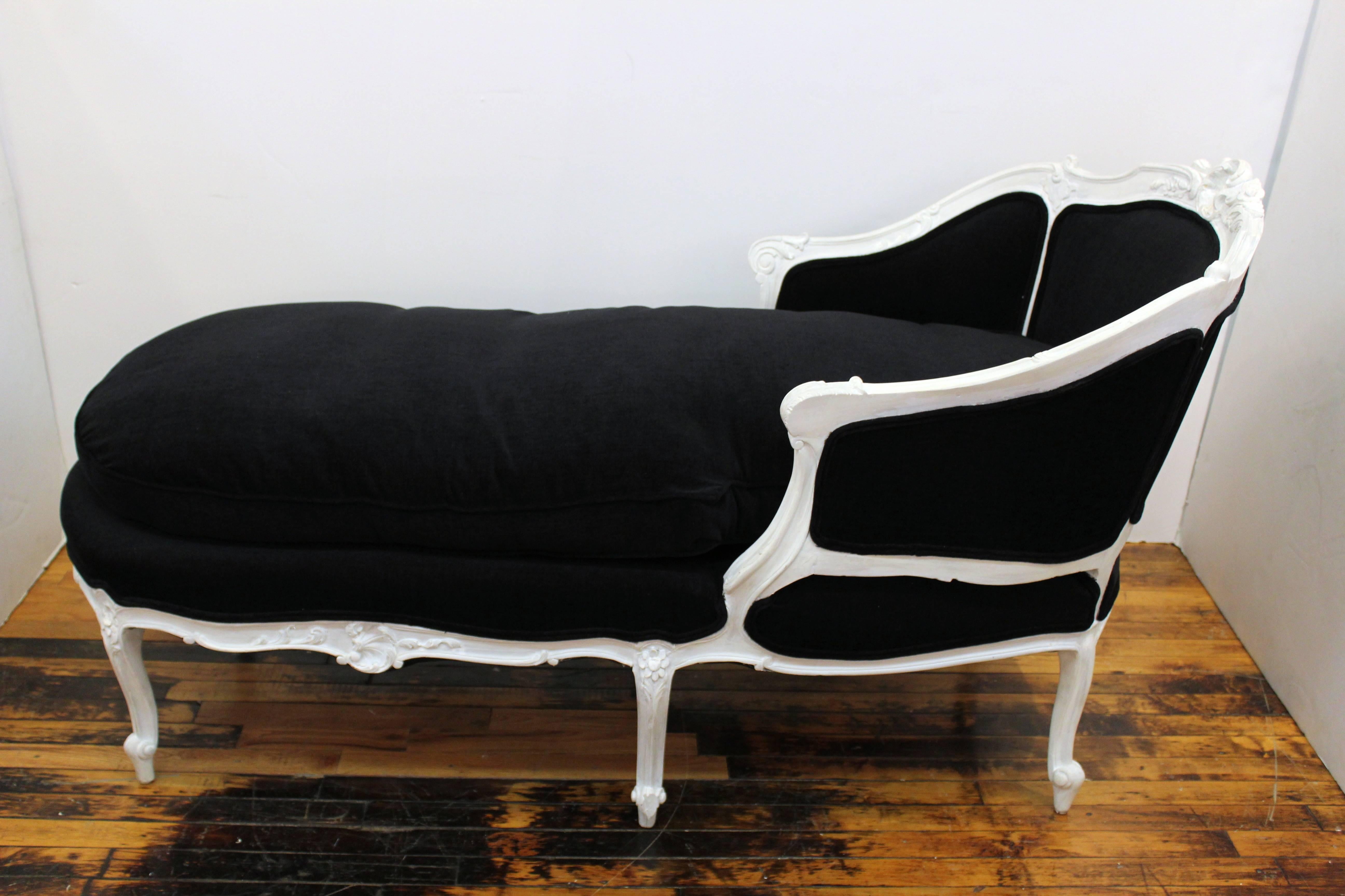 Hollywood Regency style sculpted beechwood chaise lounge made in France in the 1940s. Elaborate wood carving, recently reupholstered in black chenille. Painted white finish. In great vintage condition.