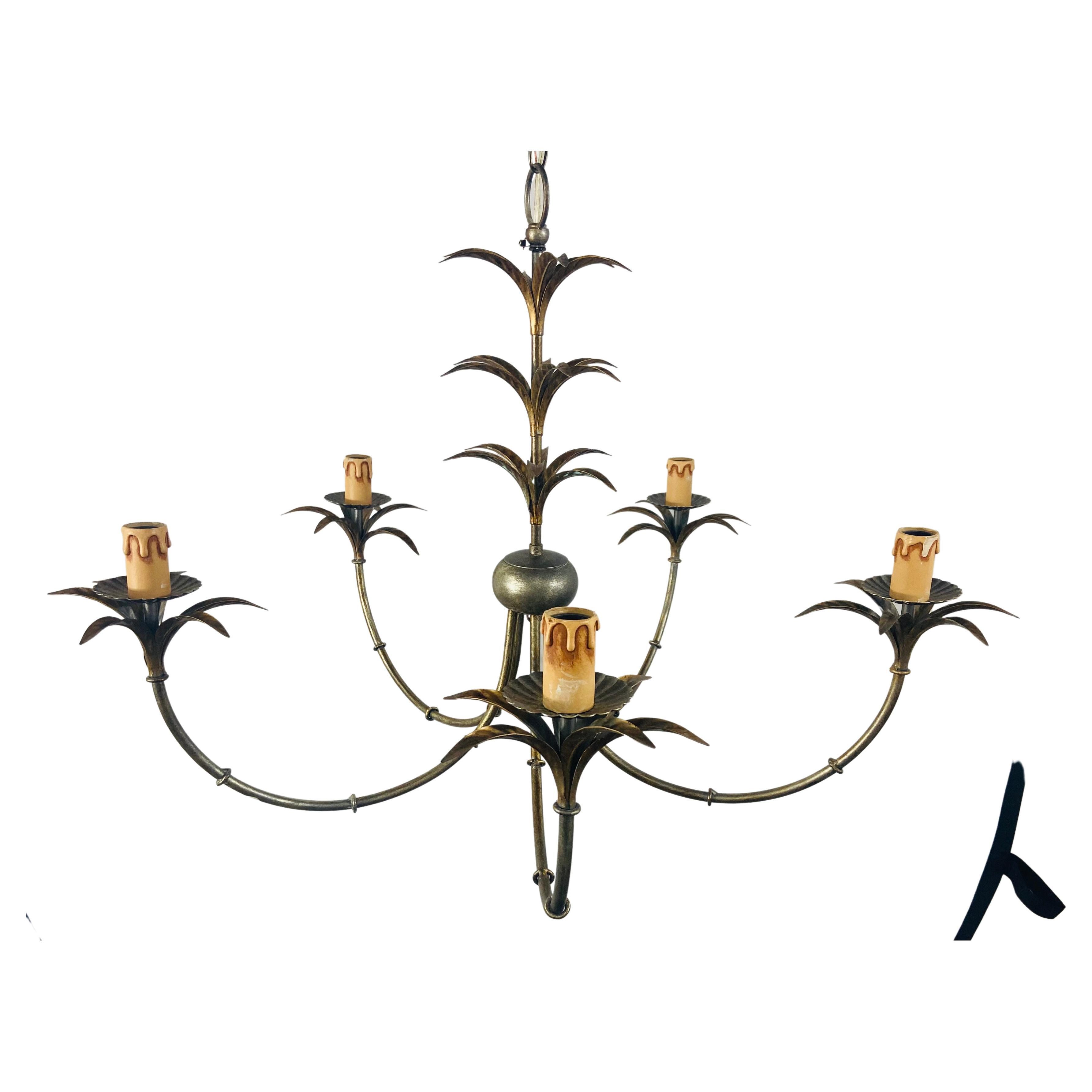 A classic and elegant French Hollywood Regency style chandelier in antique brass finish, The Chandelier has five fine arms , each arms ends in a palm tree /leaves design and holding a candelabra bulb. The chandelier column is also hand carved in the