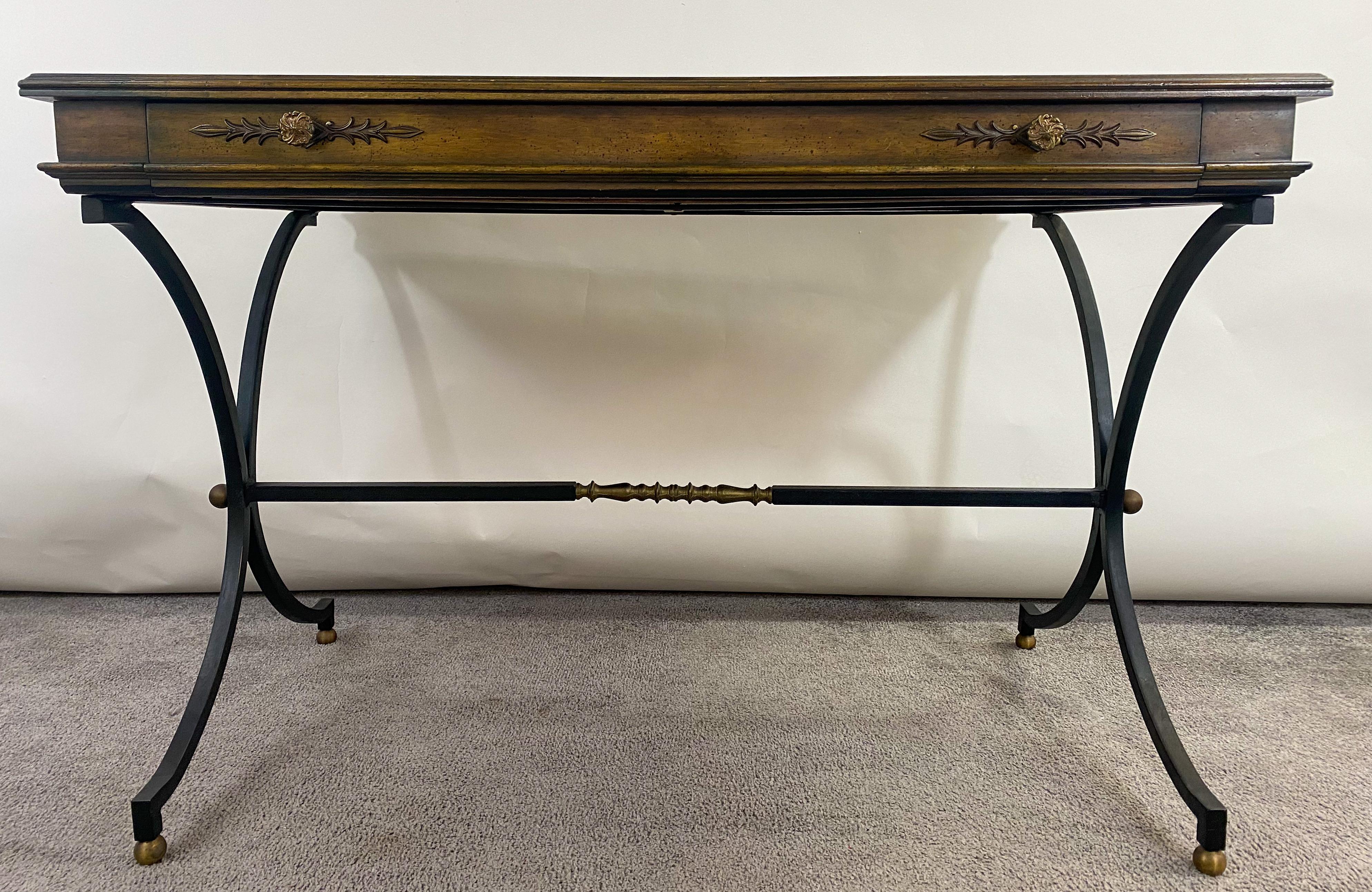 A classy mid-20th century French Hollywood Regency style writing desk. The desk is made of solid mahogany and has one large drawer standing on cast iron scissor legs with brass ornaments. The drawer is embellished with original brass pulls having