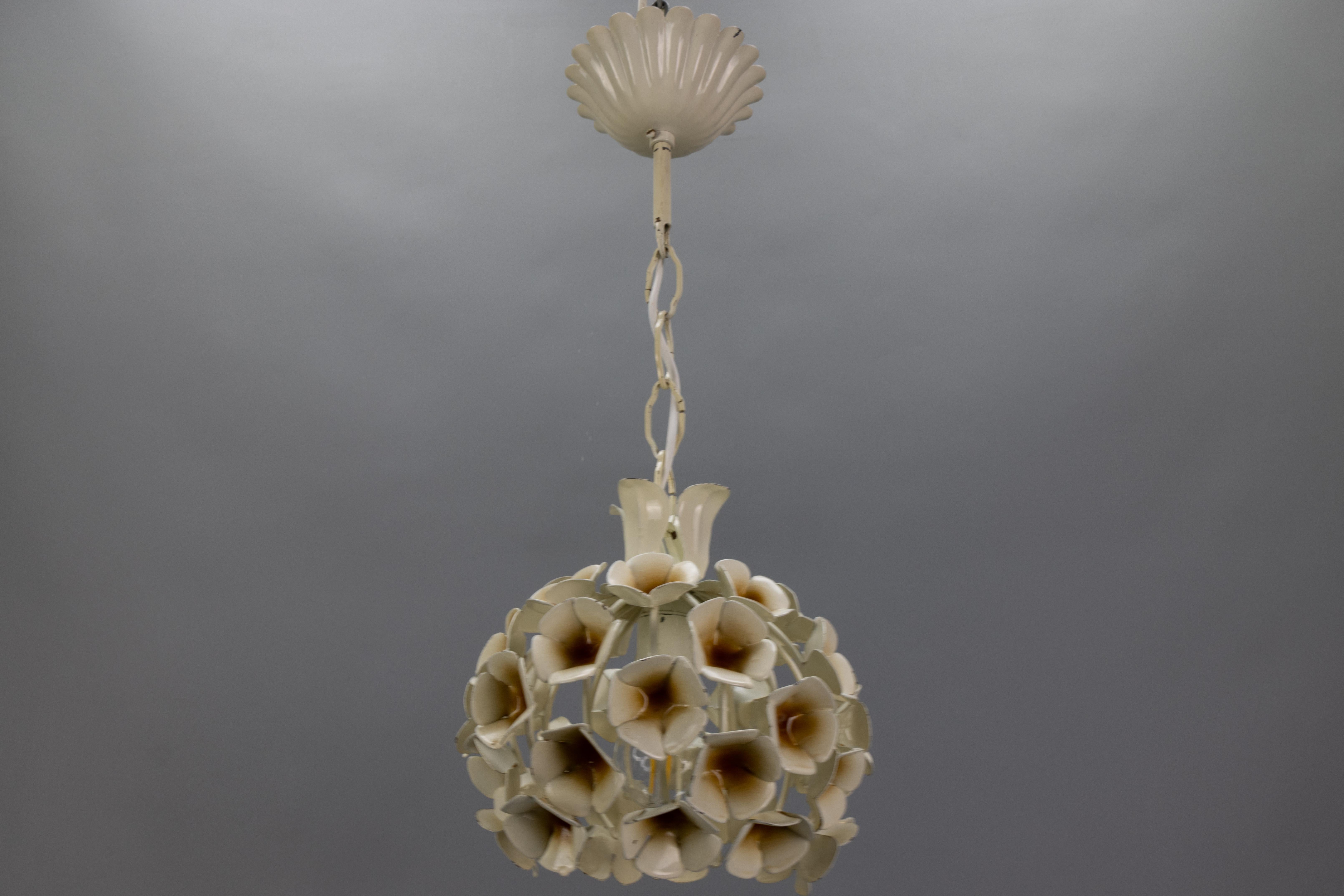 Lampada a sospensione a fiore bianco in stile Hollywood Regency francese, Francia, circa anni '60.
Questo adorabile e compatto lampadario a sospensione in metallo bianco presenta una struttura a forma di sfera decorata con fiori bianchi e accenti
