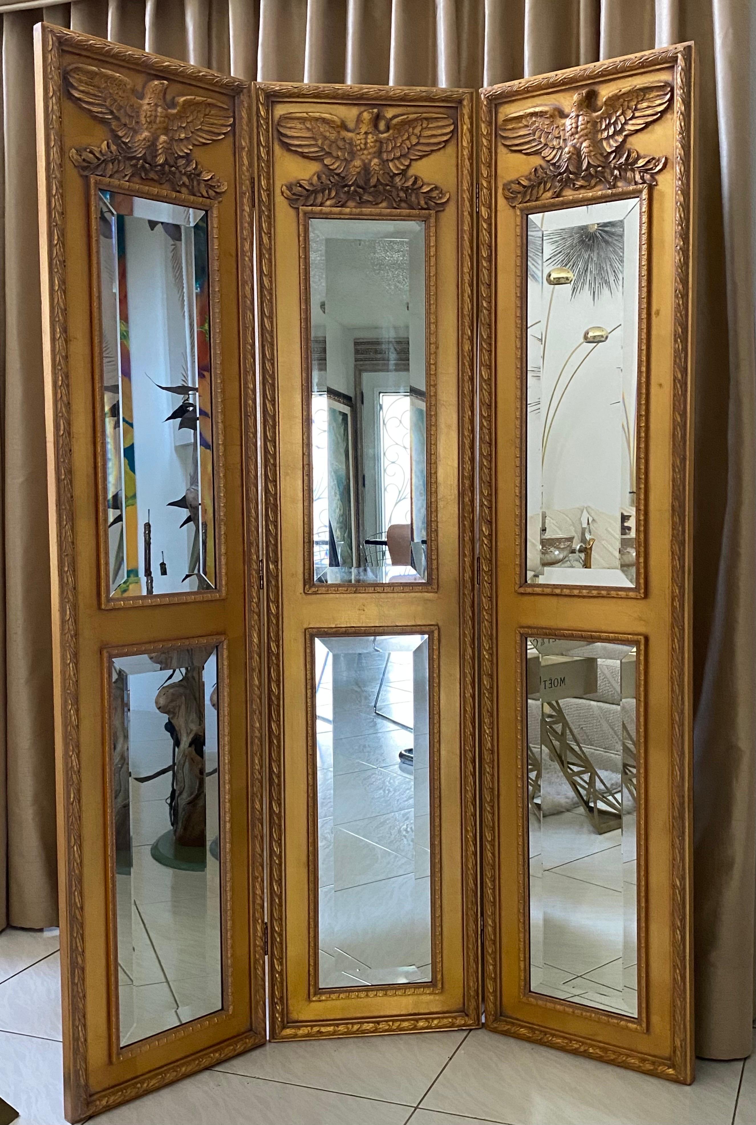 Französischer 3-fach vergoldeter Holzschirm mit Empire-Adler-Motiven und abgeschrägten Spiegeln. Die antikgoldfarbenen Paneele auf der Rückseite dieses Möbelstücks verleihen ihm aus jedem Blickwinkel ein vollendetes Aussehen. 