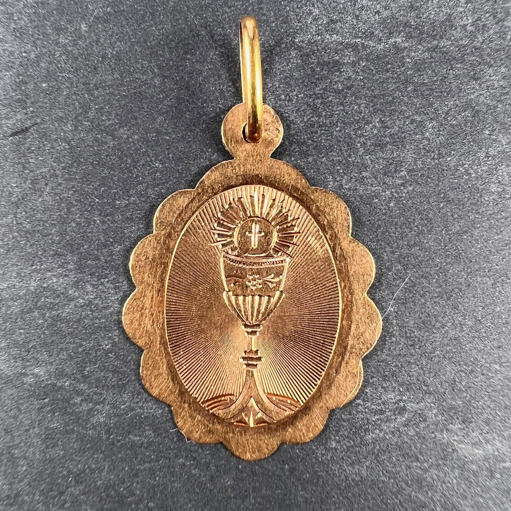 A French 18 karat (18K) rose gold charm pendant designed as an oval medal with scalloped edges engraved with the Holy Chalice in radiating lines.. Stamped with the eagle mark for 18 karat gold and French manufacture with an unknown maker's mark. 