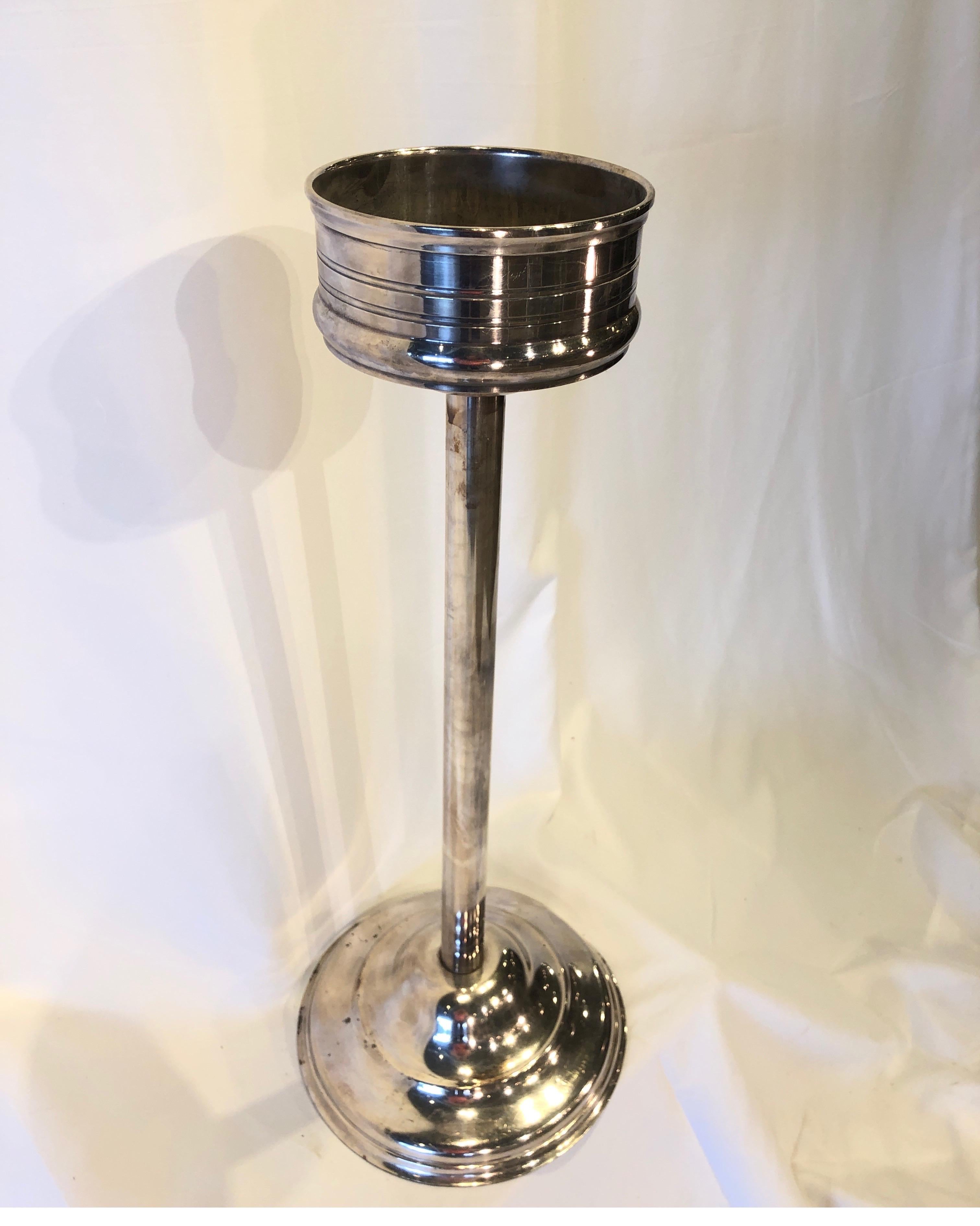 This beautiful French hotel silver champagne stand was originally used in a restaurant to hold a cooler and bottle of wine or champagne. The stand is 27.25 inches in height, 7 inch diameter top and has a 10.75 inch diameter weighted base. A