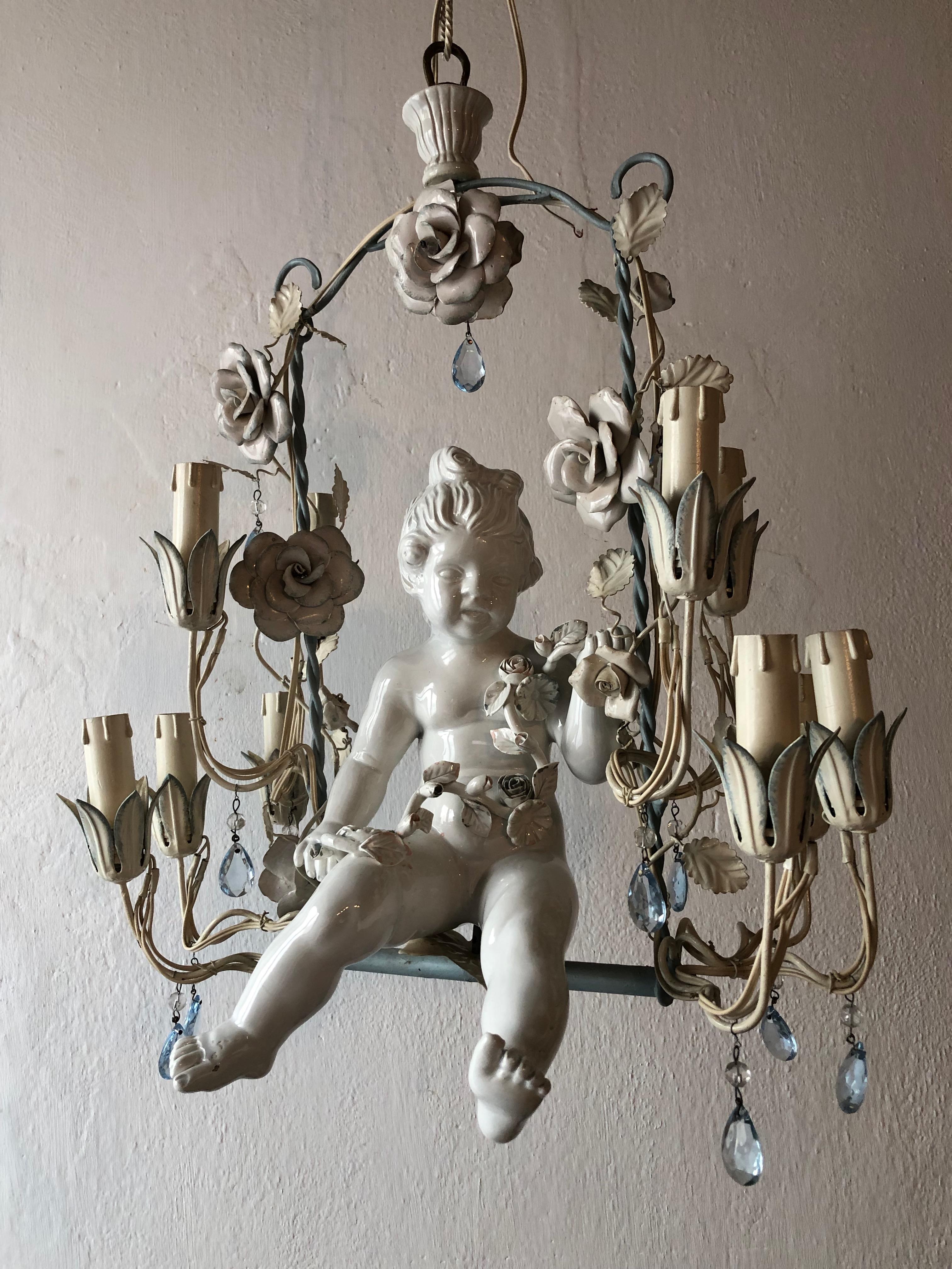 Housing 10 lights, rewired and ready to hang. French blue original tole with big white roses with blue tips and a huge porcelain cherub holding flowers swinging in the center. Adorning light blue crystal prisms. Adding 17 inches of original chain