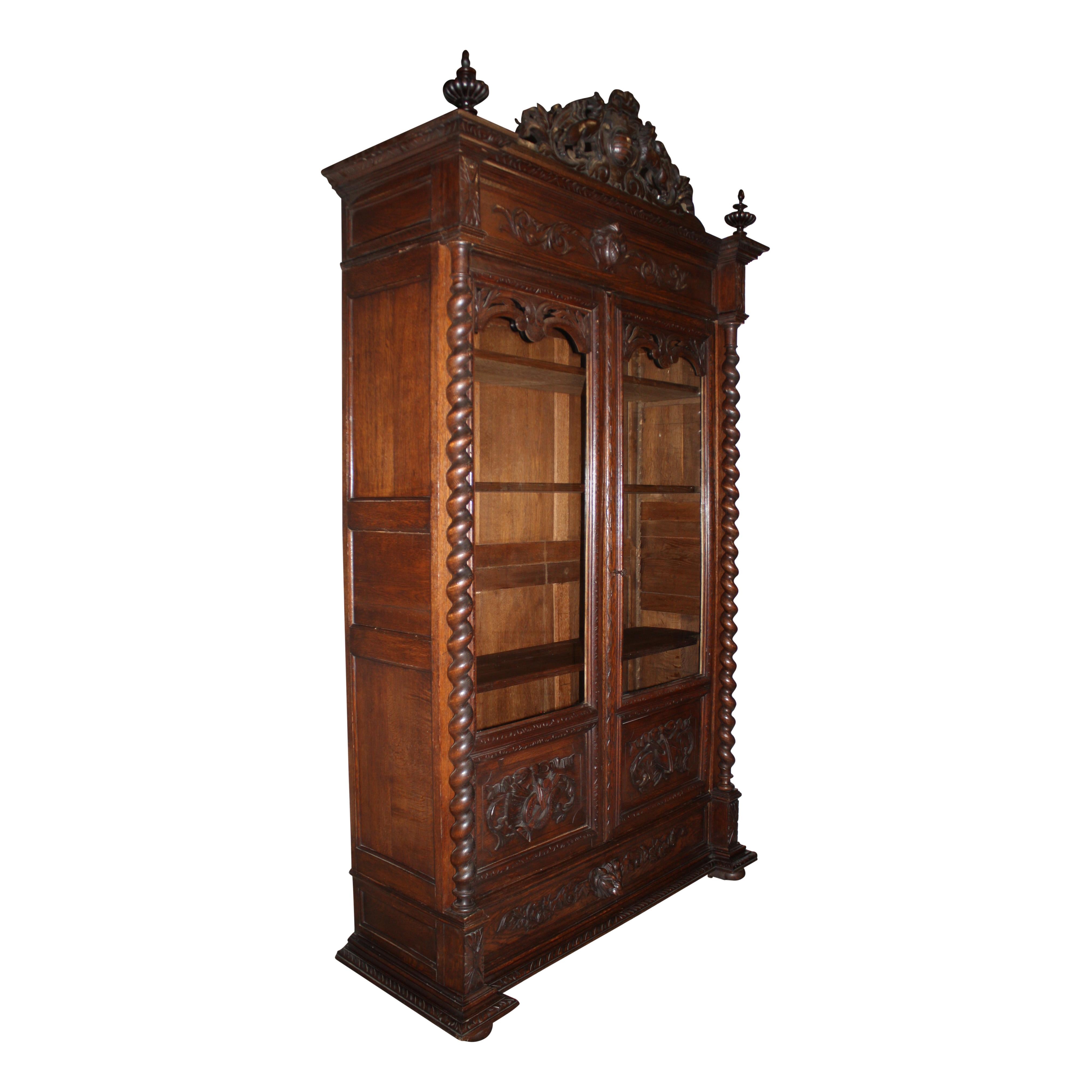 Embellished from top to bottom, this stunning bookcase features opposing griffins and gadrooning finials above a cornice of scrolled acanthus leaves around a central pineapple; lower door panels carved with a stringed instrument and an artist's