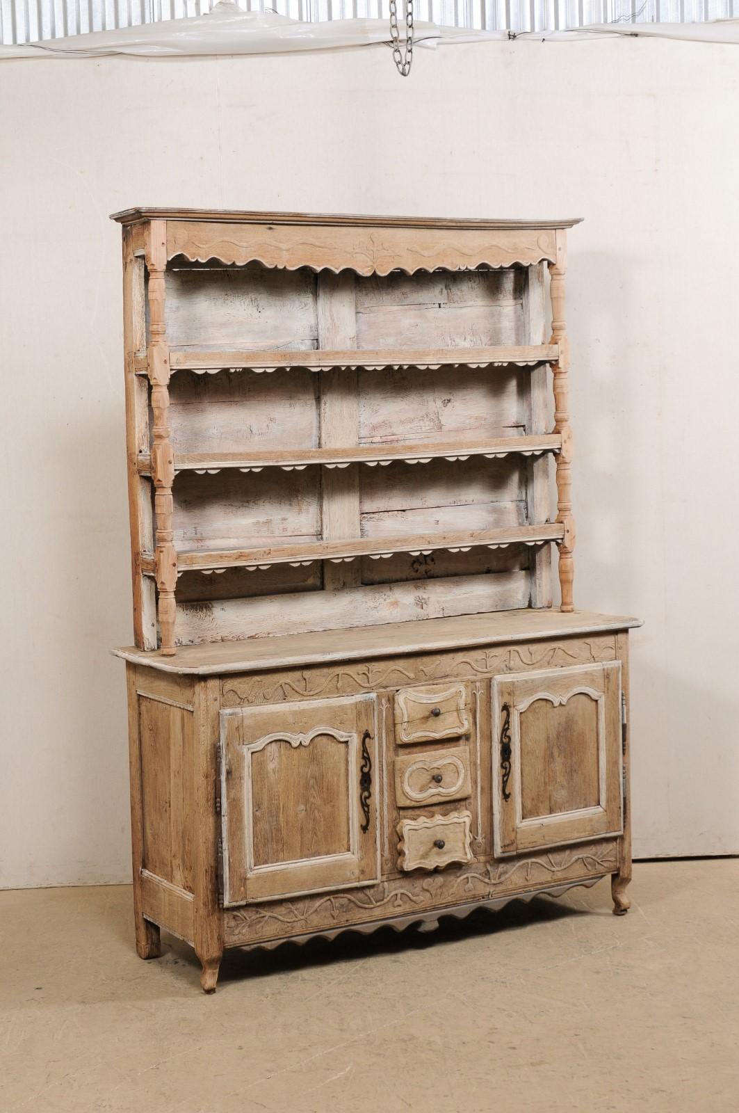 A French carved-wood hutch display and storage cabinet from the early 19th century. This antique cabinet from France features a tall hutch with beautifully scalloped cornice and three shelves for displaying dishware or china, which rests atop a