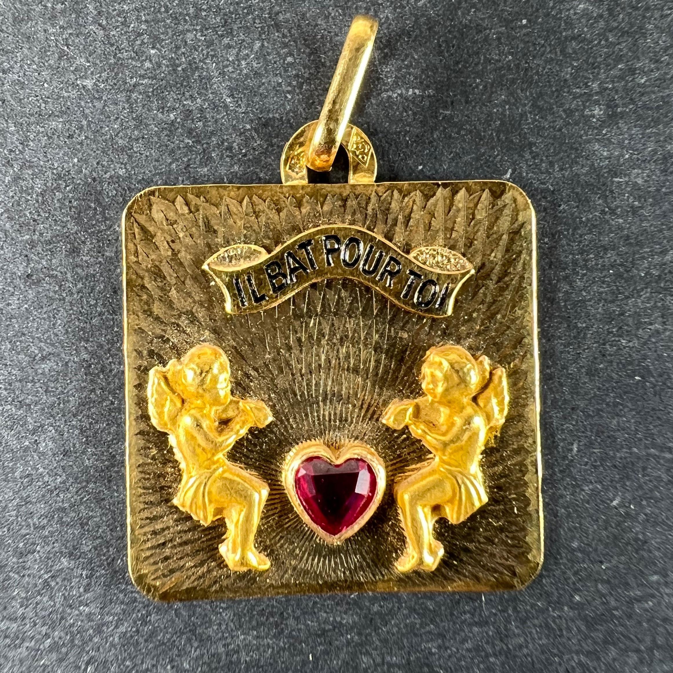 Pendente charme quadrato in oro francese 18 carati (18K), disegnato come uno sfondo a raggiera tornito a motore che irradia un cuore d'amore in rubino sintetico, con due figure di cupido in oro giallo con martelli in bilico per battere il cuore.