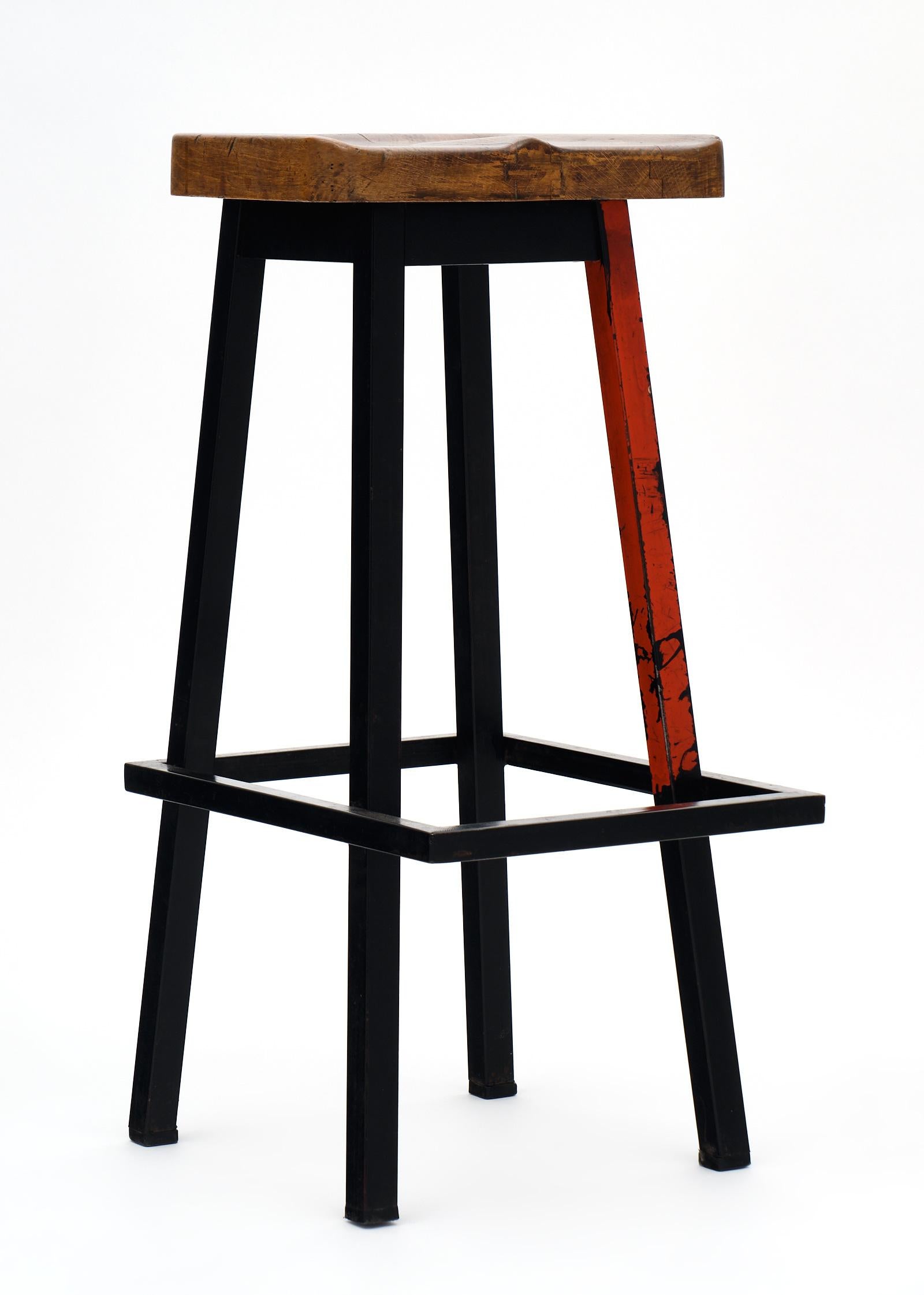 French industrial bar stools with polychrome steel structures and wood seats. The steel bases are black in color with red legs on each. We love the original patina and comfortable size. The price listed is for the set of eight, but could be sold as