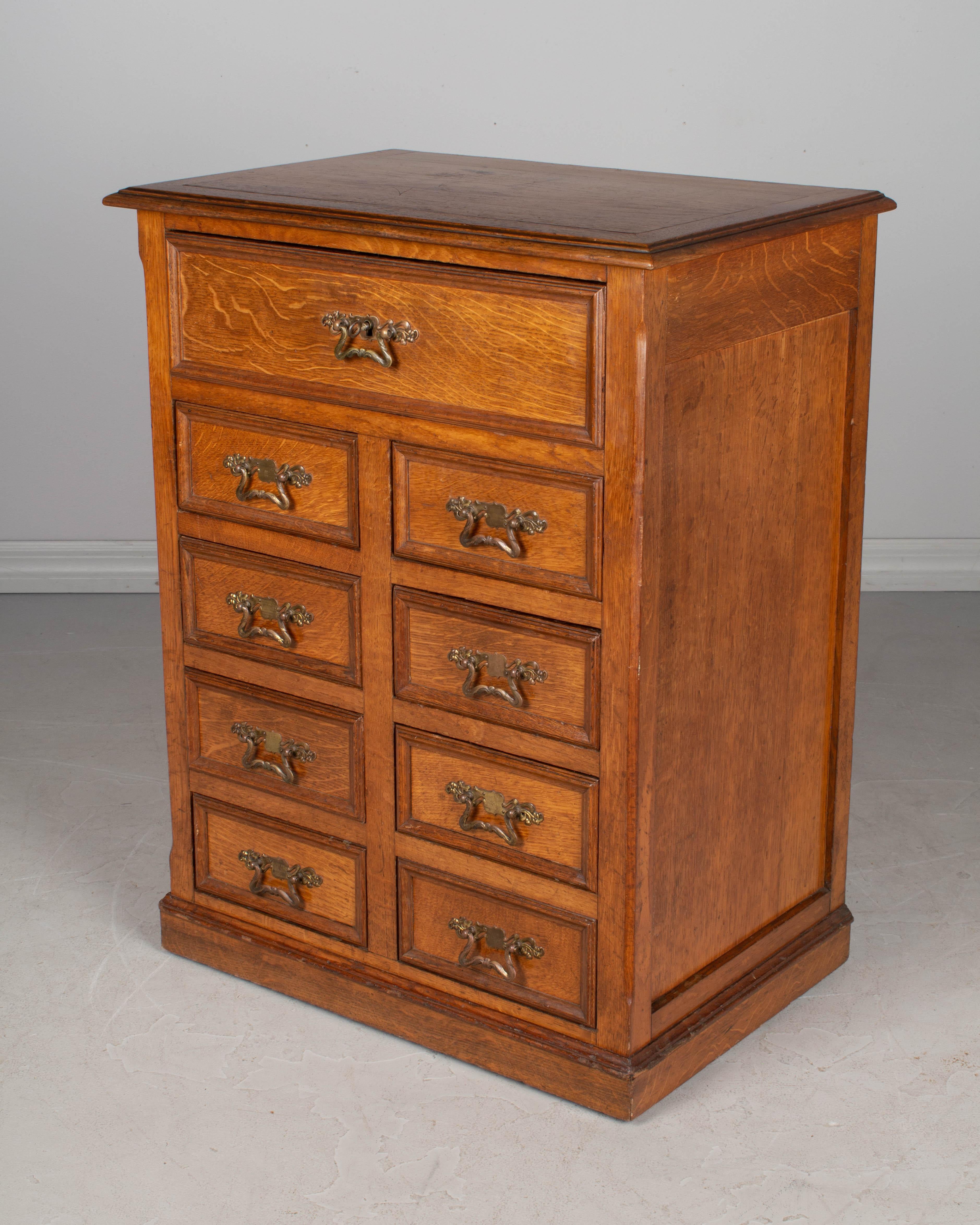 A small French meuble de métier, or industrial cabinet, made of solid oak. Nine dovetailed drawers with working locking system. The large top drawer has a key that locks the eight smaller drawers. Original Art Nouveau style cast brass hardware. A