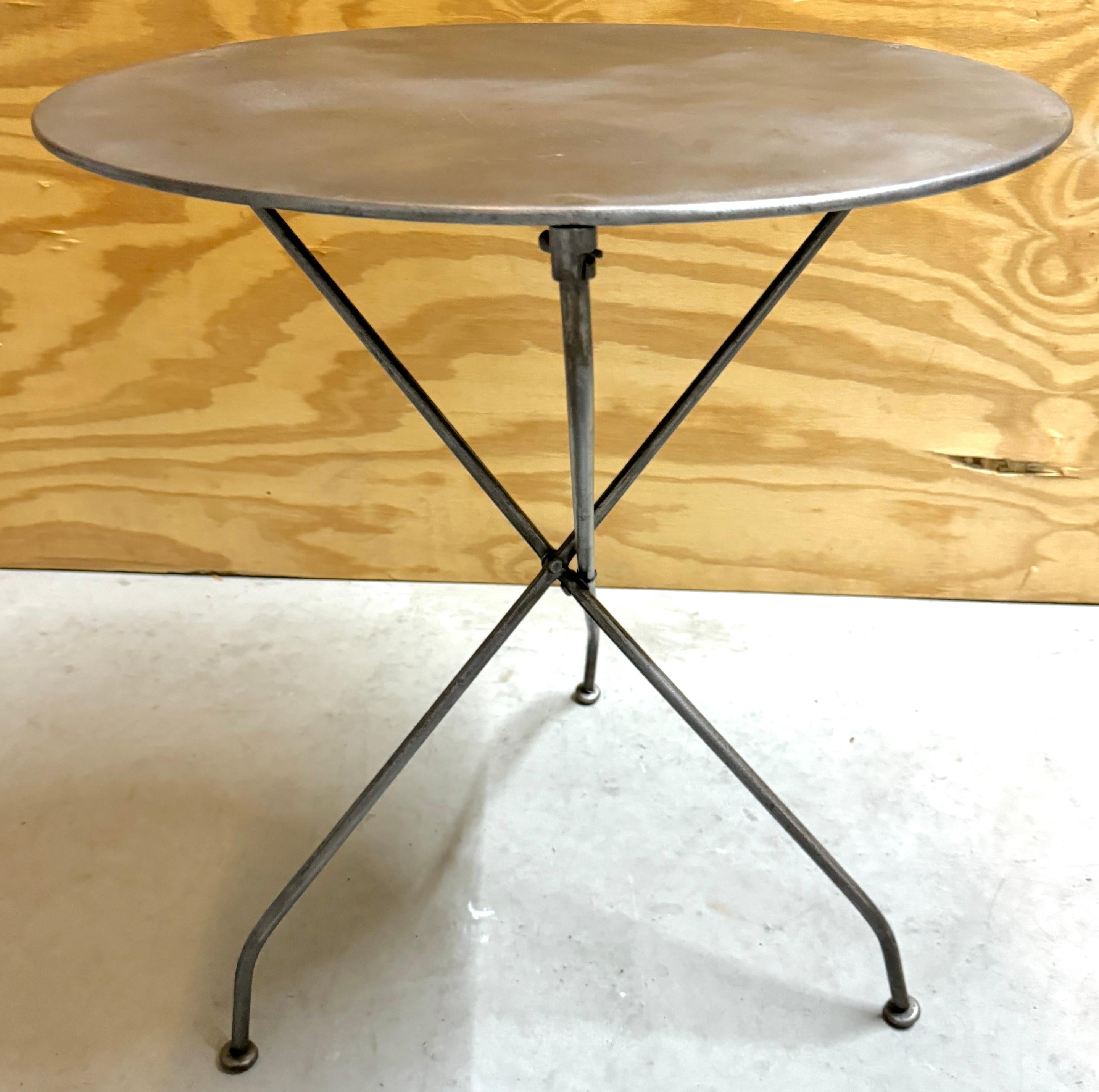Table de bistrot, de guéridon ou d'appoint en fer, pliante, de campagne, de style industriel français 
Paris, vers 1900

Un exemple magistral de design industriel français à la fois fonctionnel et élégant. D'une hauteur de 27 pouces et d'un diamètre