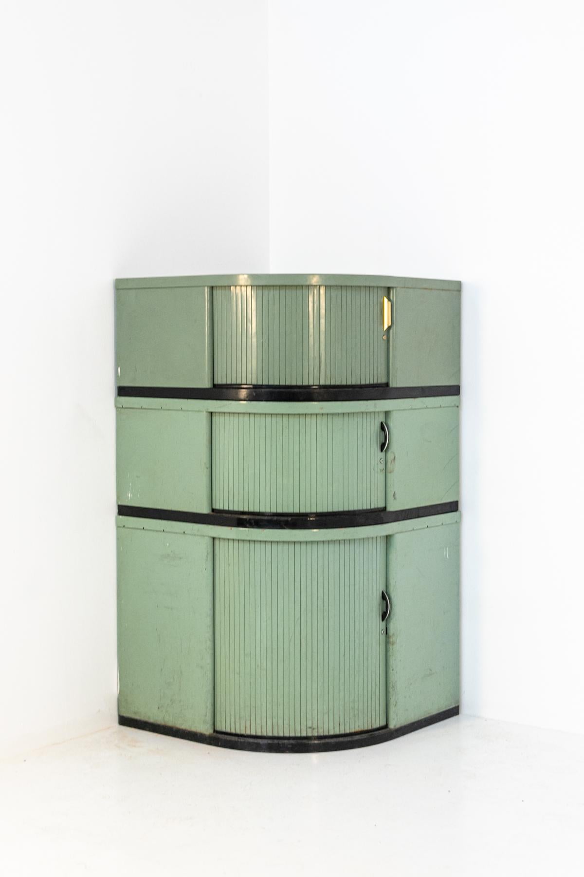French made vintage metal corner cabinet. The cabinet is in the Industrial Chic style of the 1930s. The corner unit is composed of three pieces that can be stacked together, in the middle of which there is a louver or shutter opening, which can be