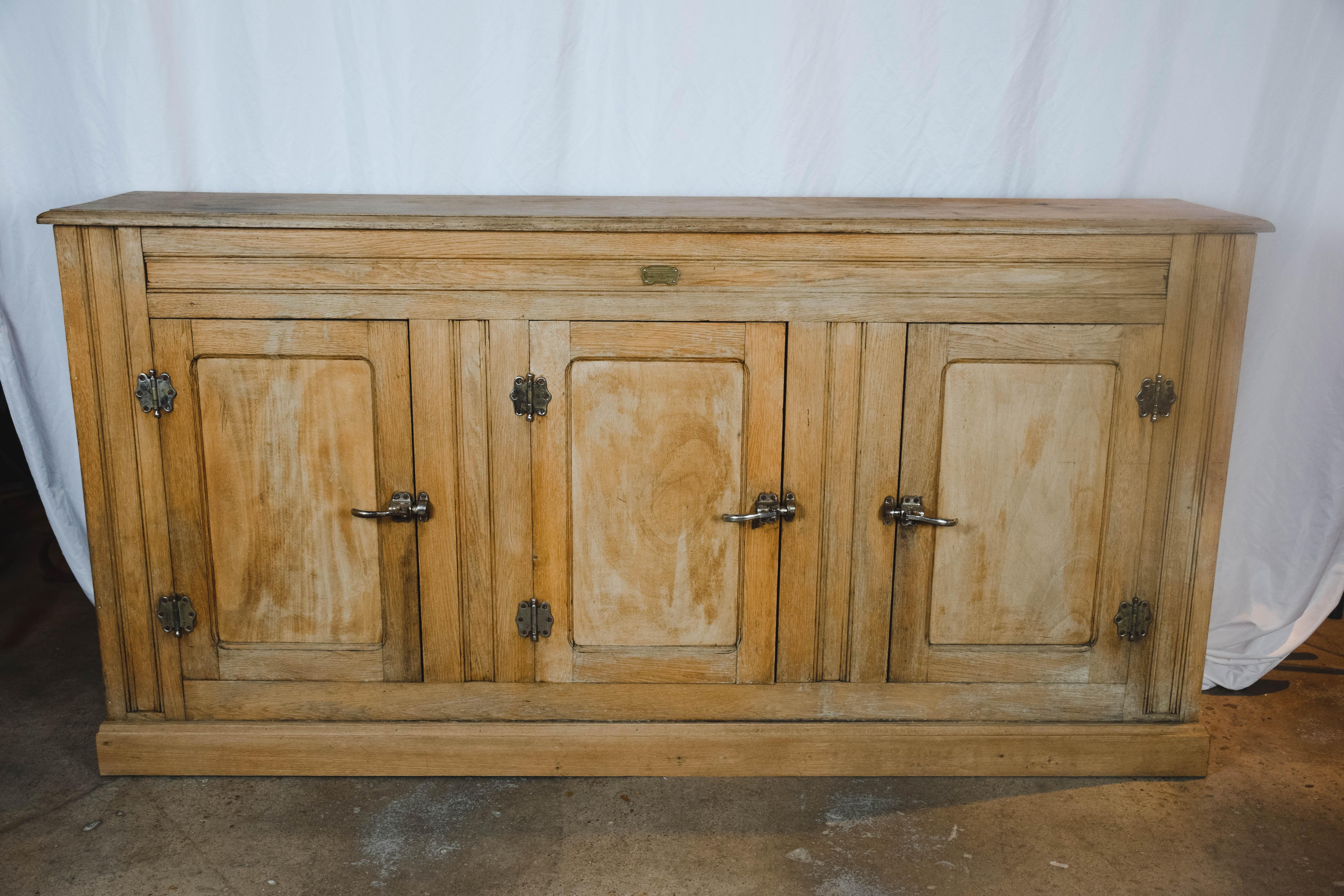 Found in France, this rustic industrial ice box cabinet in pine has original hardware, removable slatted shelves and a zinc bottom that was used to hold ice. A predecessor to the modern day refrigerator, this cabinet has a brass plate that reads