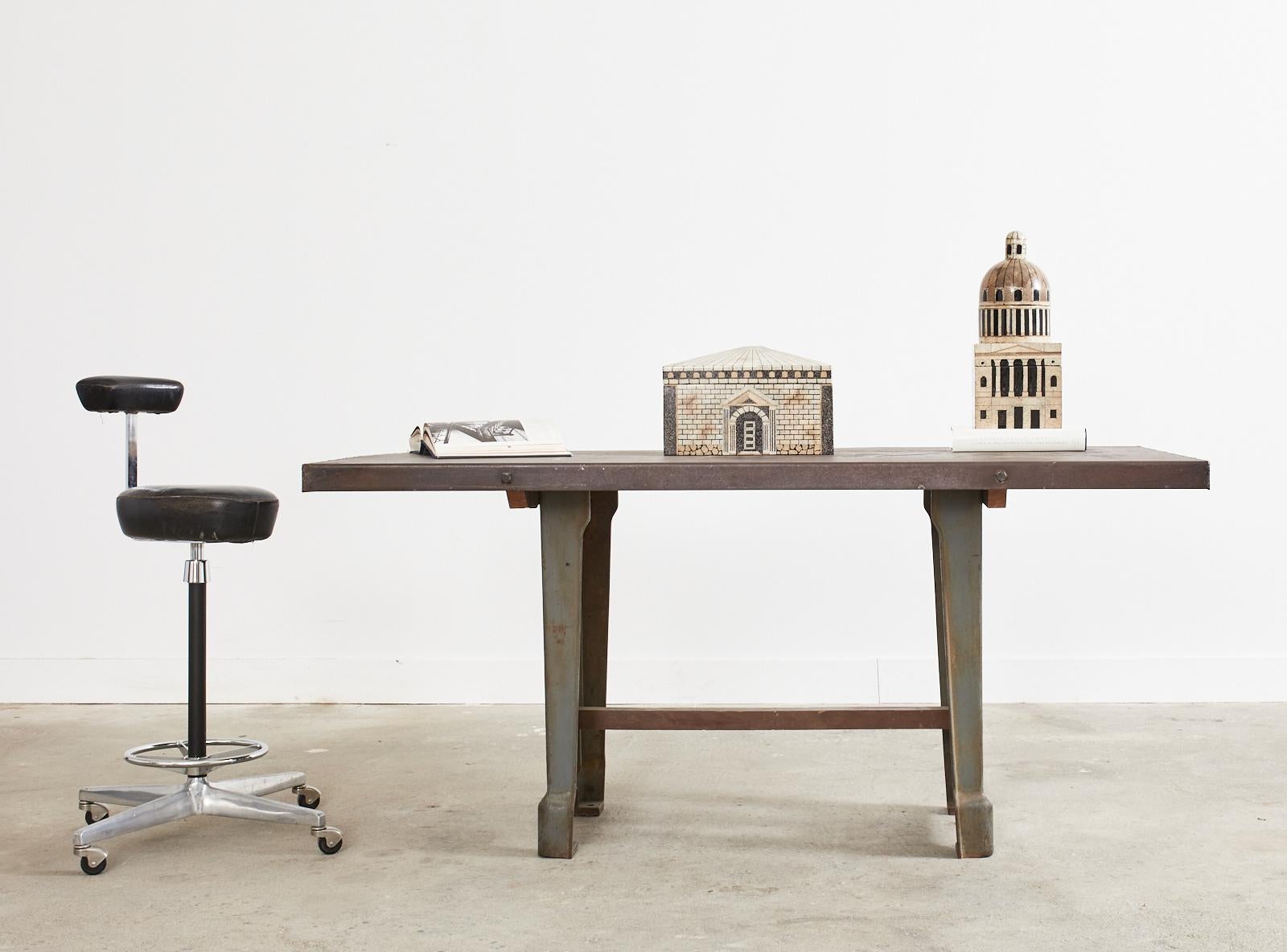 Artisan repurposed French industrial style library table or work table featuring cast iron machinist legs. The table has a hand crafted iron rectangular top conjoined to trestle style base. The top has a wonderful heavily patinated finish adding to