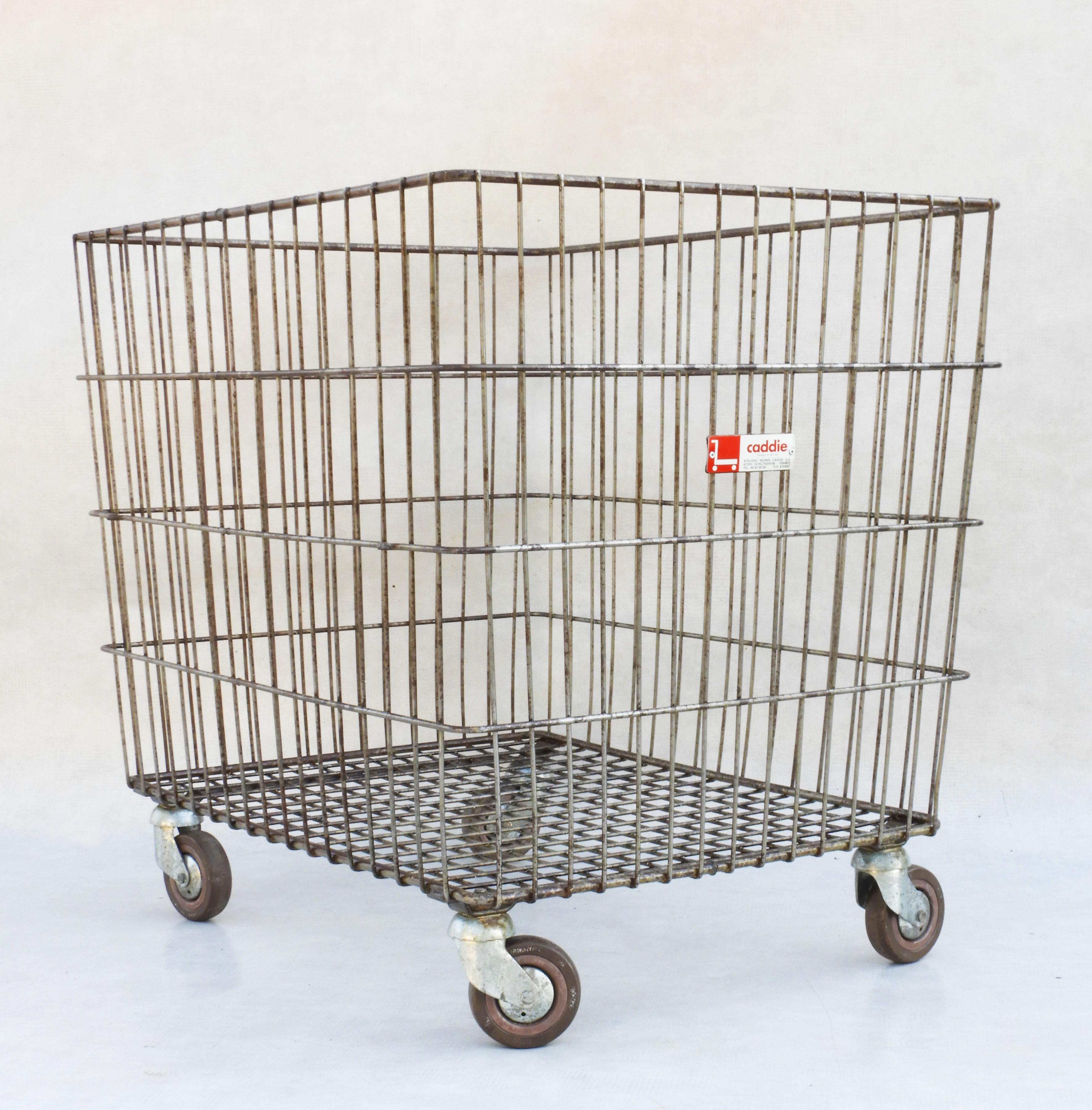 Large French industrial trolley cart from Caddie France.
Great mid-century basket in heavy gauge wire mesh on multidirectional wheels. 
Versatile and practical, indoors or out, great for storage of toys, firewood, linens, towels etc. With the