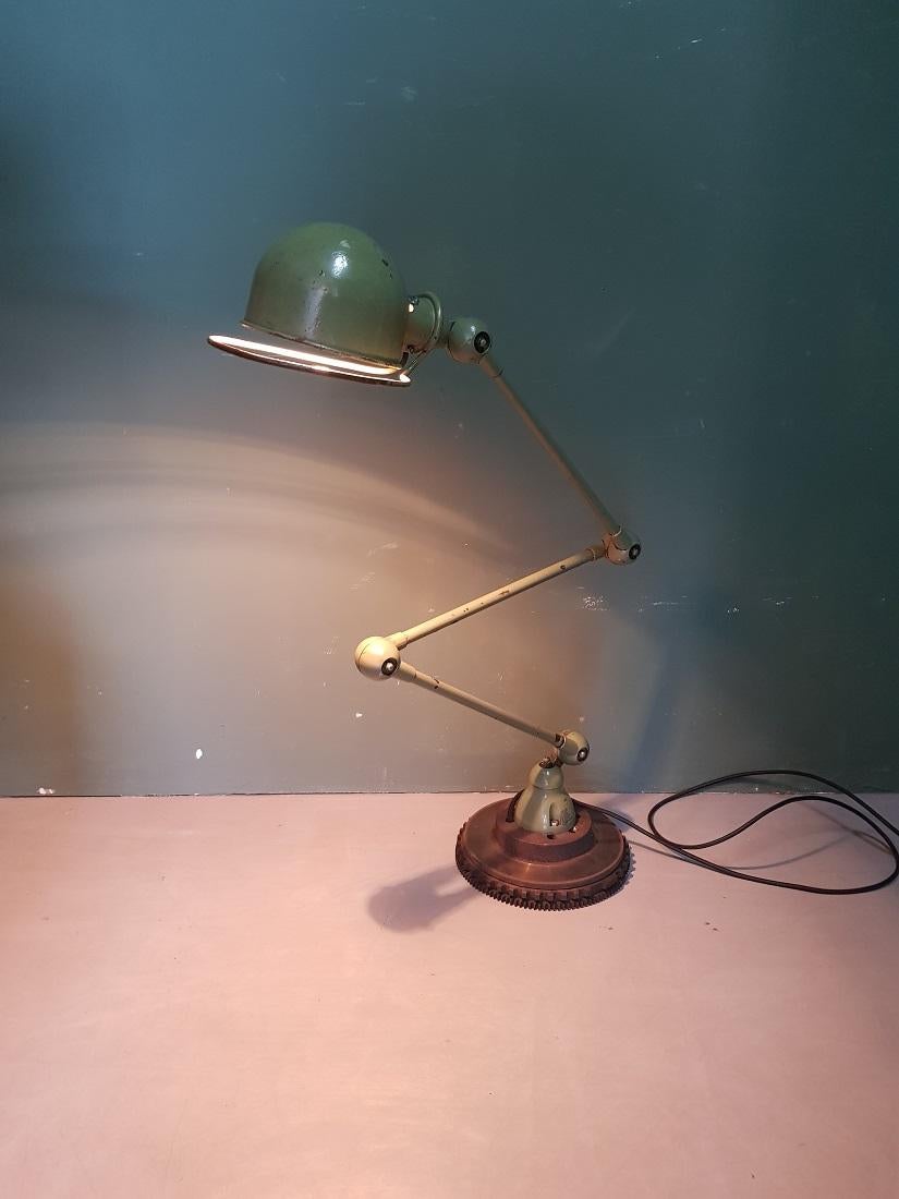 Vintage French industrial 3-arm workbench lamp from the well-known brand Jielde mounted on a brake disc with an additional counterweight a flywheel, equipped with a new cord and plug and contains a normal fitting. Third quarter of the 20th century.