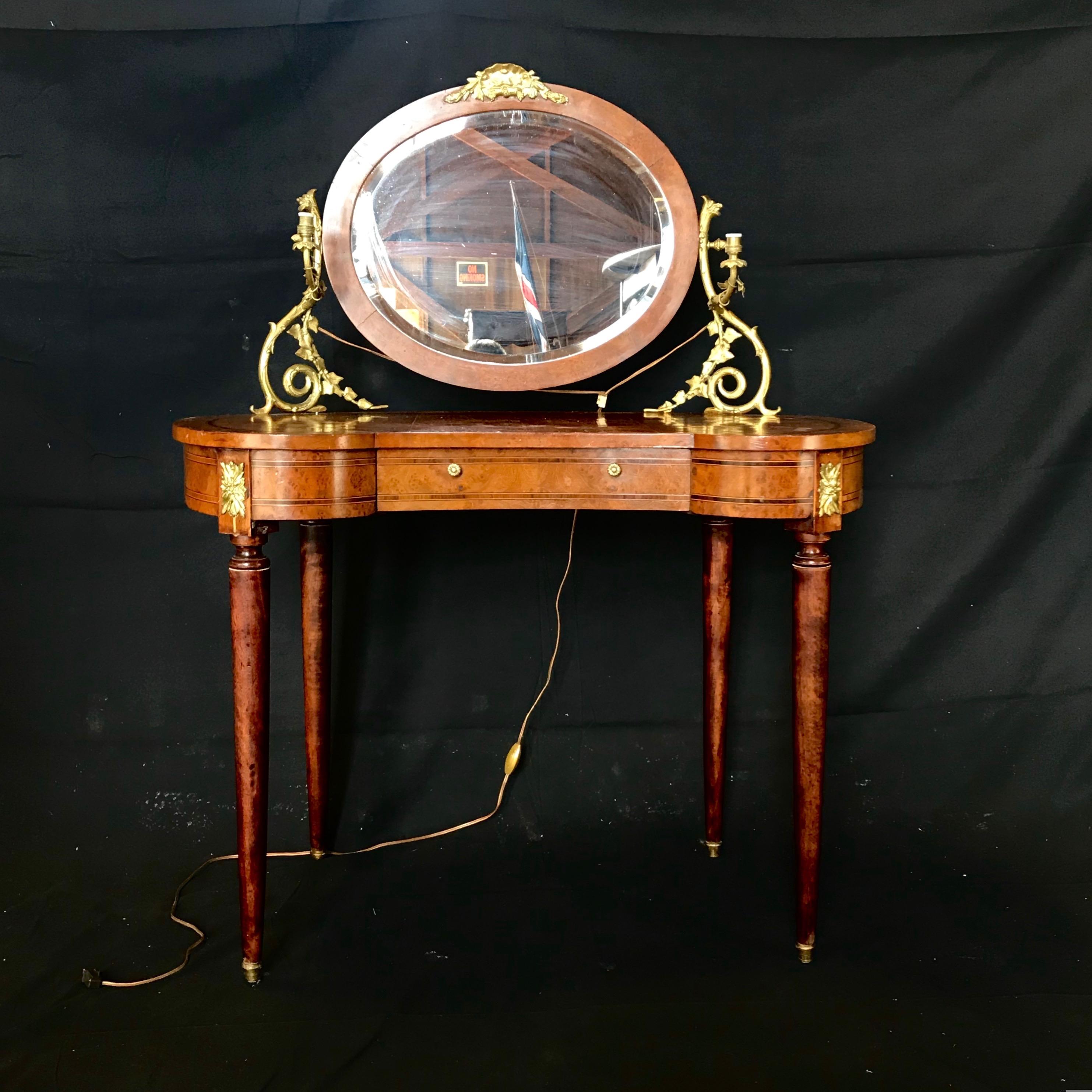 A fine French Louis XVI inlaid burled walnut gilt bronze mounted dressing table, having kidney shaped top with gilt bronze encadrement and a superstructure supporting a beveled oval mirror flanked by gilt bronze scrolling candle arms -wired to