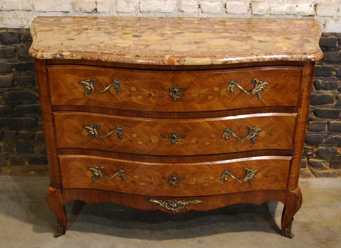 A French dresser from the mid-20th century veneered with rosewood.
The dresser or commode has a beautifully curved front with three drawers. The rosewood veneer is made in cross band and is inlaid with natural and floral motifs typical for the