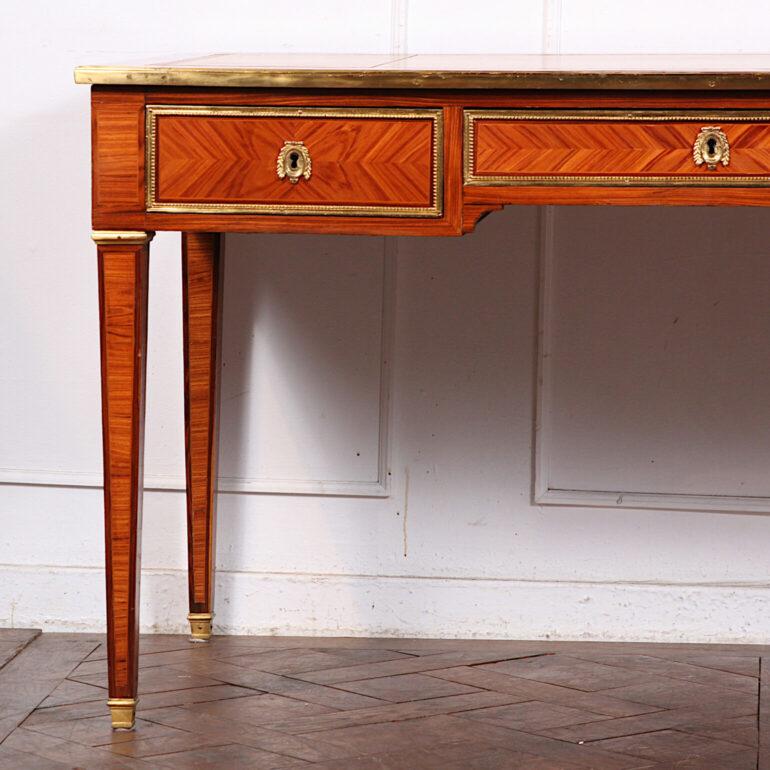 Exceptional quality 19th Century French inlaid Kingwood marquetry Louis XVI style bureau plat with highly polished and detailed gold gilded bronze mounts and a leather hand gold tooled writing surface of saddle color leather. A stunning desk with a