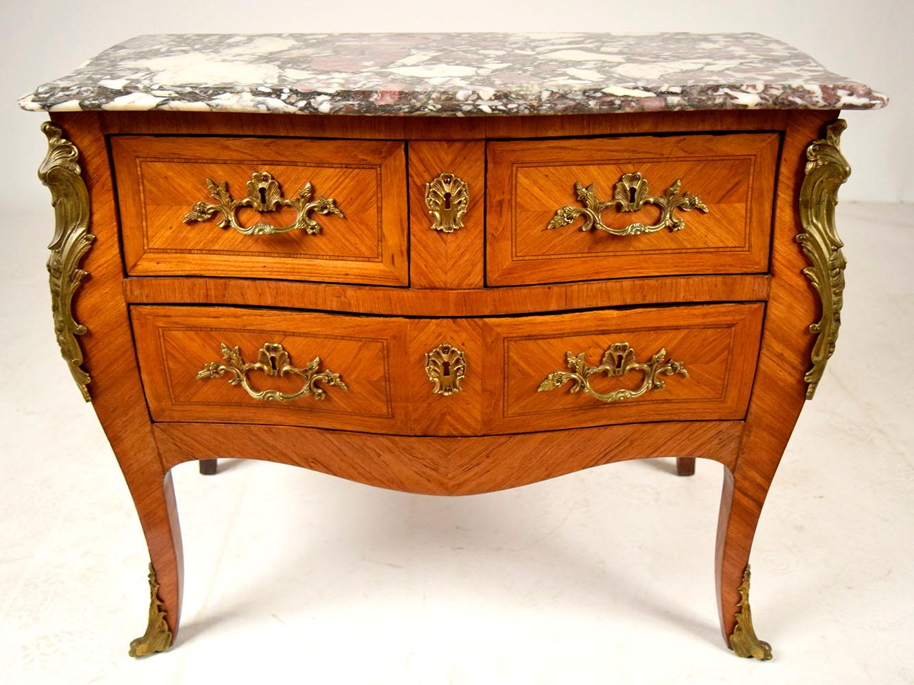 This Antique French Louis XV Style Chest of Drawers has been professionally restored, is made out of solid wood, and has an intricate inlaid design with a newly polished patina finish. The commode features a multicolored beveled marble top, two