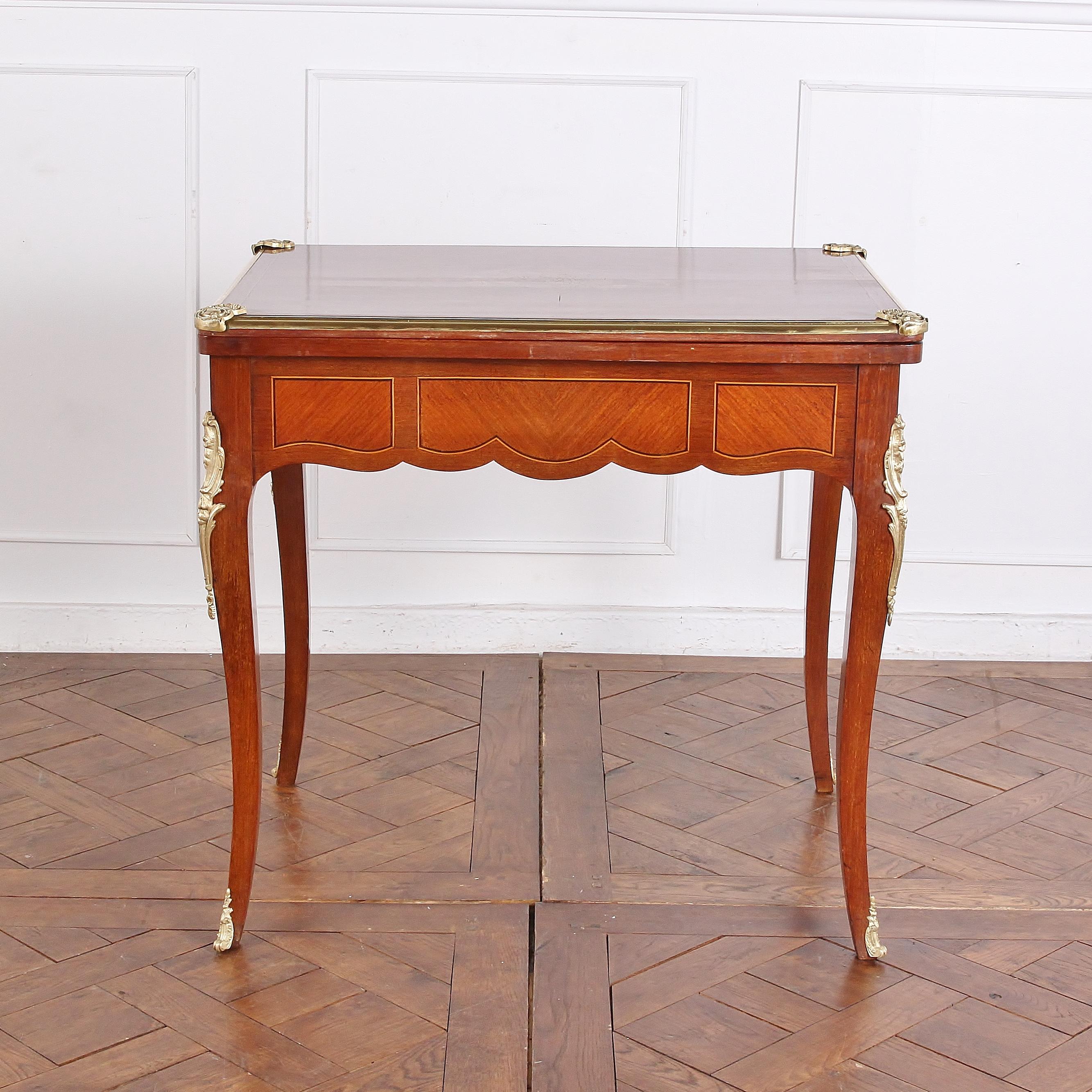 French, inlaid kingwood, Louis XV style ‘flip-top’ games table, with ormolu mounts and edging around top surface. The top opens to become a large felt playing surface. A drawer in one end provides convenient storage for cards and gaming pieces, and