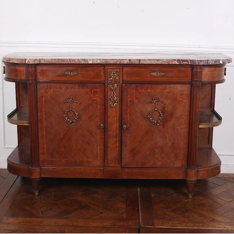 French Louis XVI buffet in figured mahogany with detailed inlaid banding and finely-cast gilt bronze ormolu mounts. Two drawers over a pair of cabinet doors and with further quarter-round side drawers over open shelves with pierced brass galleries.