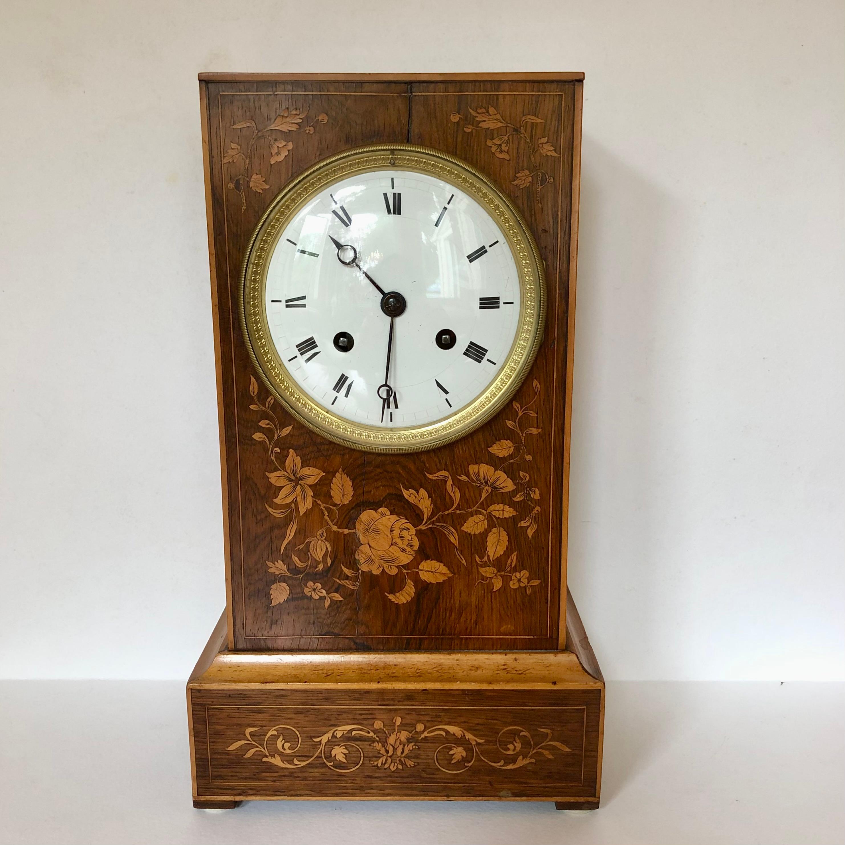 A beautifully made, French, inlaid rosewood mantel clock from 1820, with 8 day striking movement and silk-suspended pendulum. Original porcelain dial mounted in brass. The marquetry features lovely stylized flowers that contrast perfectly with the