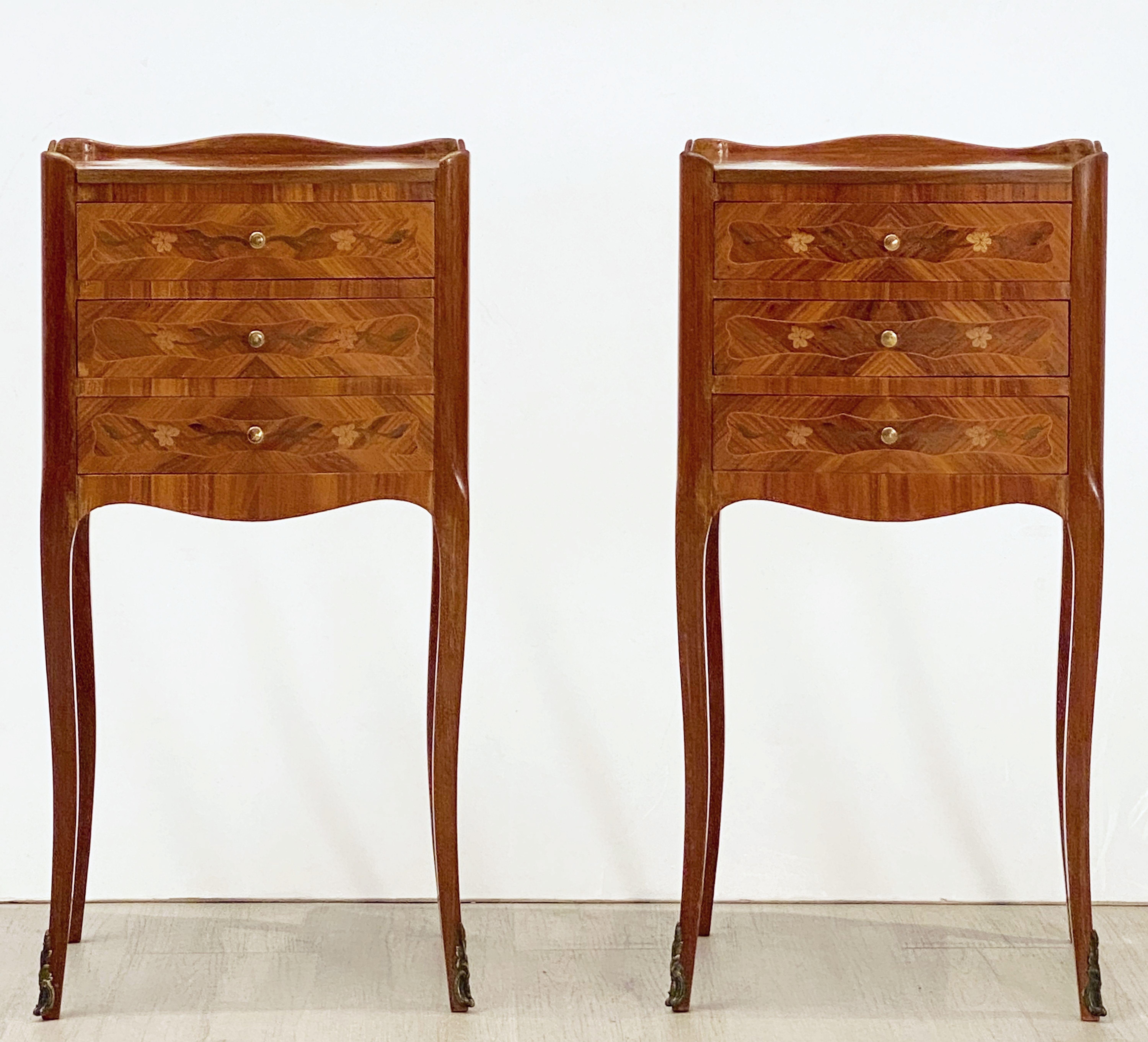 A fine pair of French bedside end tables or nightstands, each stand featuring an inlaid top with serpentine gallery over a frieze.
Both with three inlaid drawers with brass pulls, marquetry sides and apron bottom, and set upon four cabriole legs