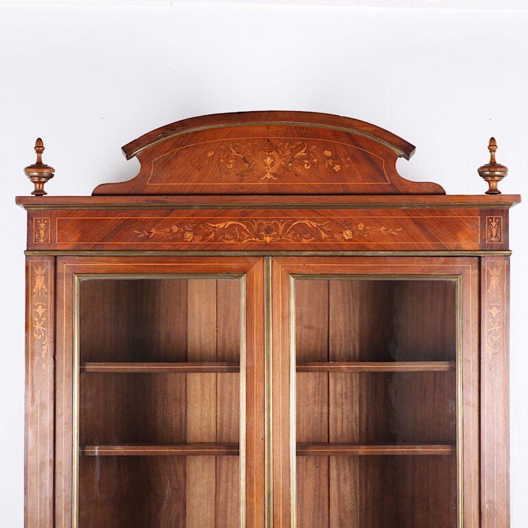 A French inlaid rosewood two-door bookcase with fine scrolled and floral inlay, the top with inlaid crown and finials, the doors opening to four adjustable shelves. Molded bronze accents to the doors and panels. 

 